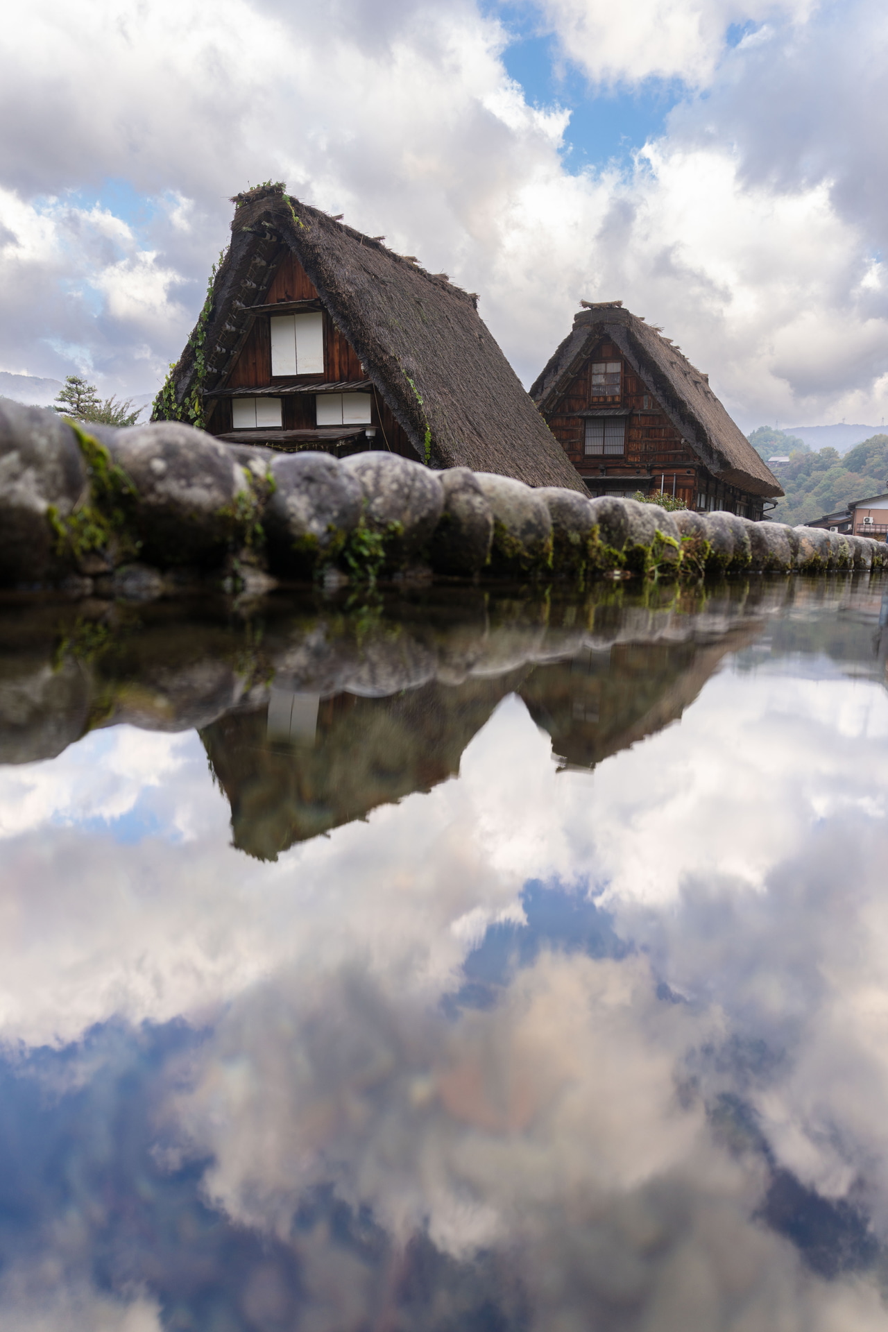 雨上がりの白川郷。水たまりに風景が映り込んでいたので、片手で水面ギリギリまでカメラを近づけて撮影した。不安定な姿勢の撮影でも、軽量でF2.8のこのレンズならぶれずにしっかり写してくれる<br><span class="fnt-85">ソニー α7R V／24mm／絞り優先AE（F2.8、1/250秒、－0.3EV）／ISO 100／WB：オート</span>