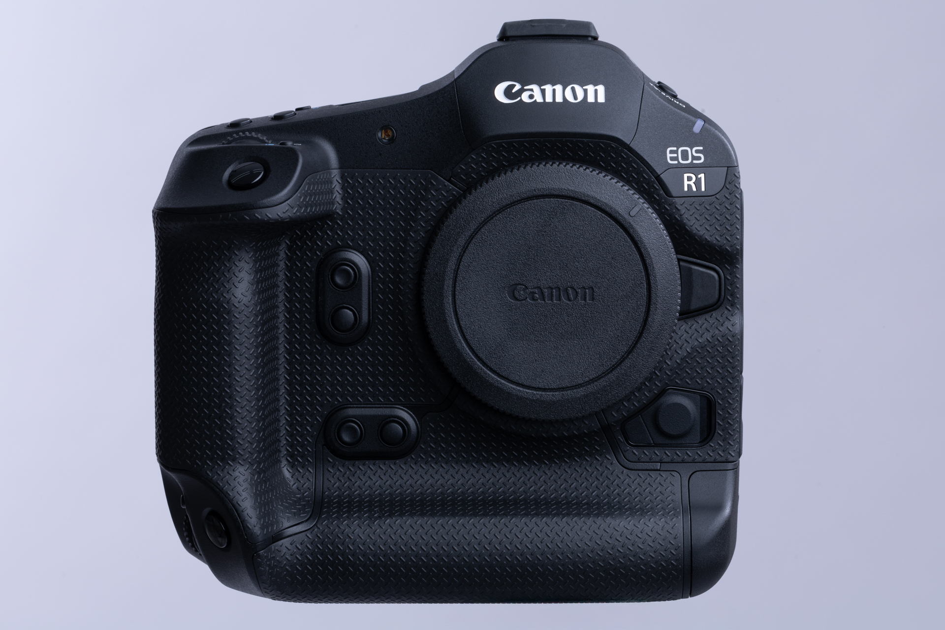 歴代のEOS-1系を踏襲した曲線を多用した縦位置撮影グリップ一体型のボディ。EOS R3との連続性を強く感じさせるがグリップ部からの貼り革（エラストマー）のパターンはR3の丸型ディンプルから金属製非常階段の滑り止めパターンを連想させるクロスパターンに。貼られる範囲もレンズマウント上部にまで及んでいる