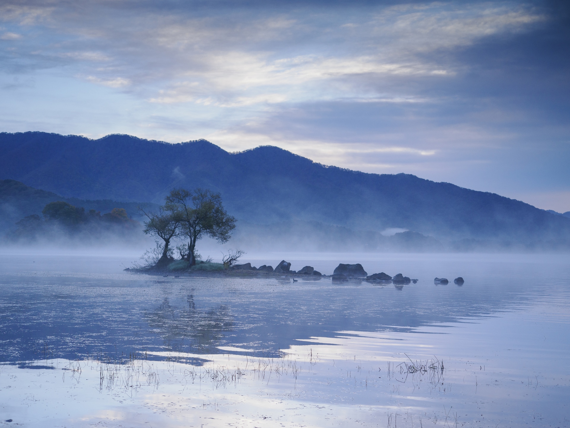 冷え込んだ朝に湖⾯から気嵐がわき立つ幻想的な情景。カメラに搭載されたライブGNDを使うために三脚を使い、実像と鏡像の露出を調整して仕上げた<br><span class="fnt-85">OMDS OM SYSTEM OM-1 Mark II／M.ZUIKO DIGITAL ED 12-40mm F2.8 PRO II／28mm（56mm相当）／マニュアル露出（F2.8、1/100秒）／ISO 400／WB：晴天</span>