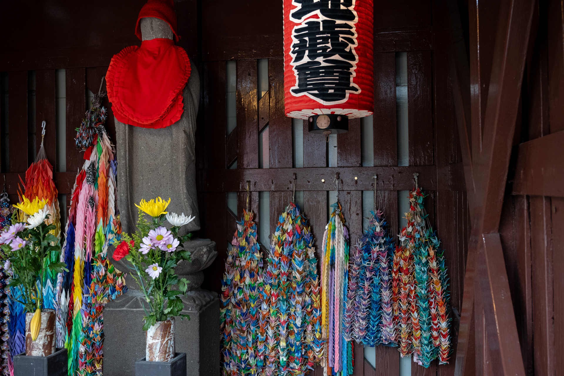 薄暗いお堂の中です。フォーカスは手前の花に合いに行きましたが、実焦点距離が24mmなので、そのまま撮影しました。被写界深度内ですから問題ないですね。<br><span class="fnt-85">ニコン Z50II／NIKKOR Z 24-70mm f/4 S／24mm（36mm相当）／絞り優先AE（1/80秒、F5.0、−1.3EV）／ISO 800</span>