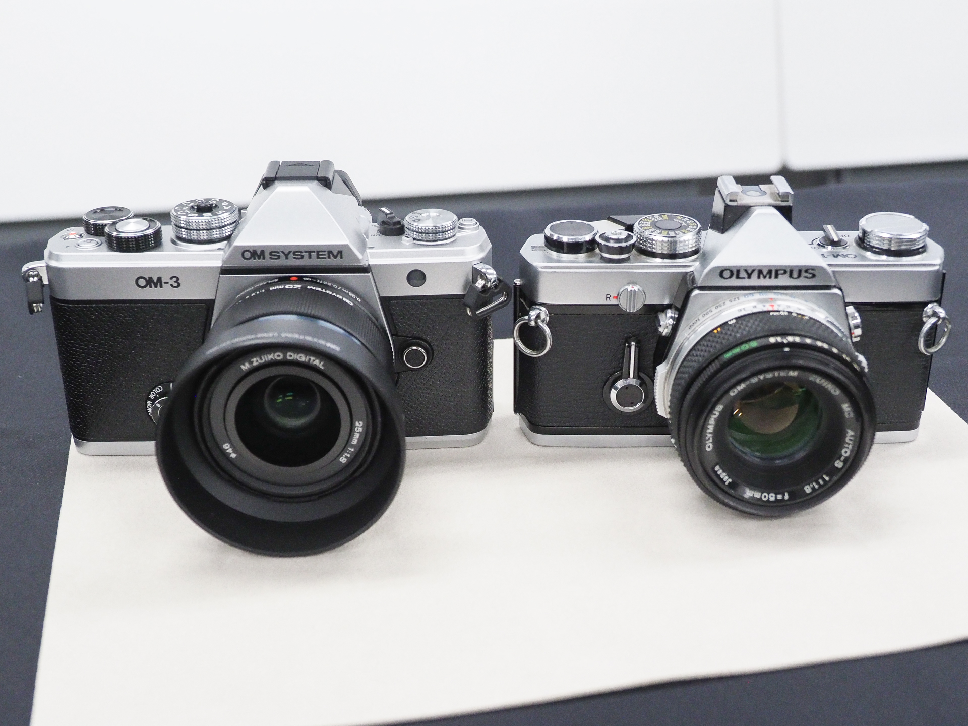 左が「OM SYSTEM OM-3」、右がフィルムカメラの「OLYMPUS OM-1」。細かなダイヤル形状の違いにも目を向けると面白い