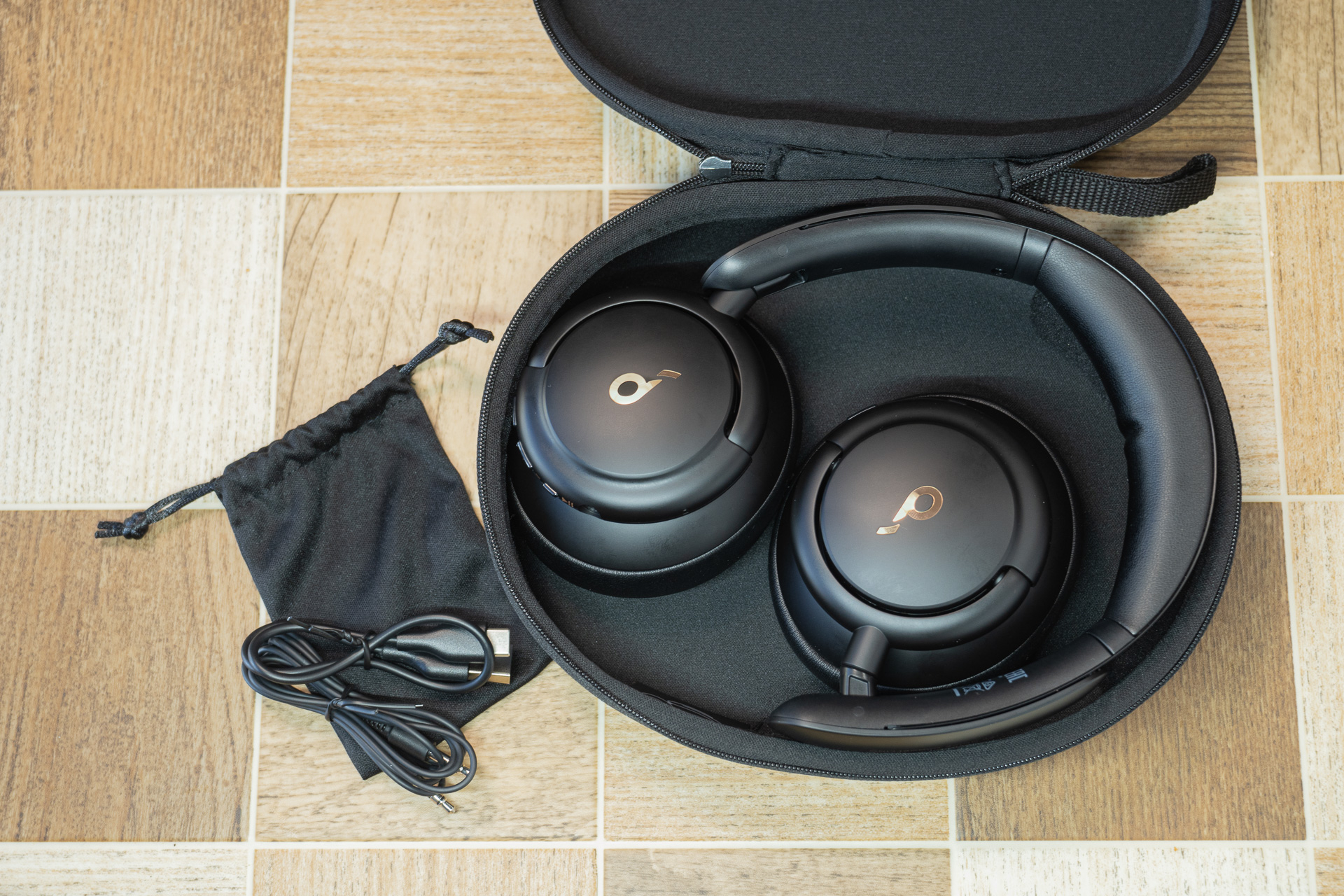 ヘッドフォン部を折りたたみ付属のケースに入れるとこんな感じ。薄く持ち運びがしやすいケースです。隣の袋は付属品。充電用のUSBケーブルと3.5mmのステレオケーブルが付属しています。ケーブルでも音源に接続できてハイレゾモード、より高音質になるそうですよ