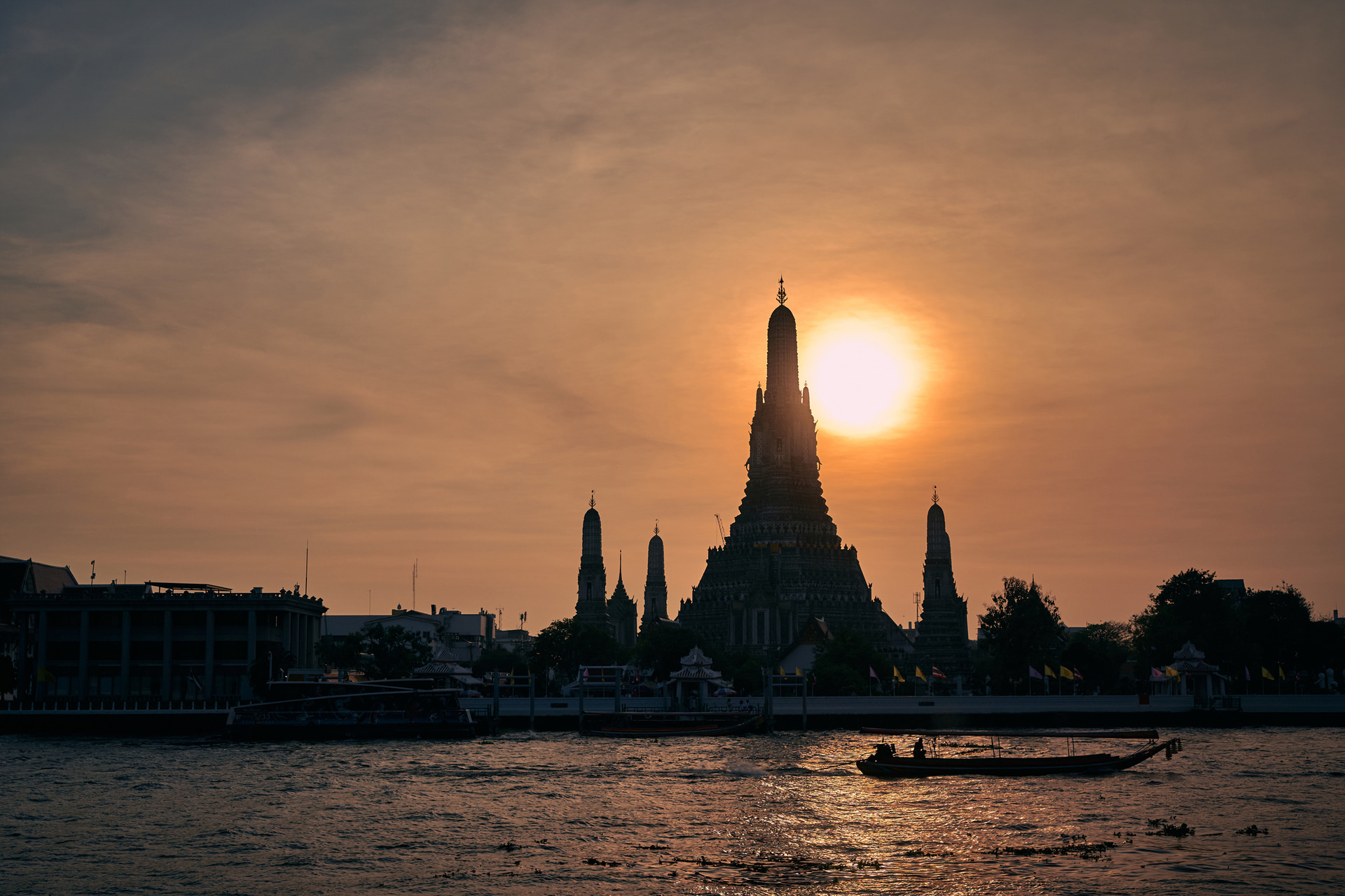 チャオプラヤ川の向こうに沈む夕日と暁の寺、ワット・アルン。川面にきらめくリフレクションの上をちょうど船が通りかかったタイミングで撮影。ハイブリッドオートフォーカスは厳しい逆光の中でも迷うことはなかった<br><span class="fnt-85">ライカSL3-S／ライカ バリオ・エルマリートSL f2.8-4/24-90mm ASPH.／50mm／マニュアル露出（F5.6、1/250秒）／ISO 320／WB：オート</span>