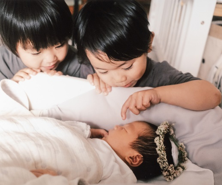 【「お気に入りの1枚」部門】タイトル：ようこそ ぼくたちの赤ちゃん…／出展者のメッセージ：生まれたばかりの弟に手作りの花かんむりをかぶせてくれたお兄ちゃん達。優しい眼差しが愛おしくてシャッターを切りました。