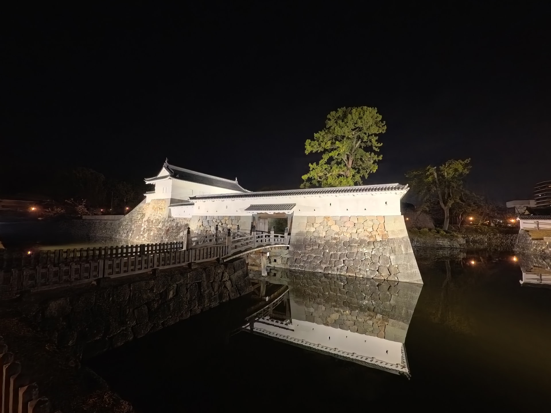 銅門桝形内仕切門のライトアップ。1秒のシャッター速度で住吉堀の水面を滑らかにした。ISO 800近くでもノイズによる劣化は感じられない。白漆喰の塀や石垣のディテール、水堀のシャドウ部から浮き上がる建物のリフレクションが美しい<br><span class="fnt-85">13mm相当／プログラムAE（F2.6、1秒、±0EV）／ISO 786／WB：オート</span>