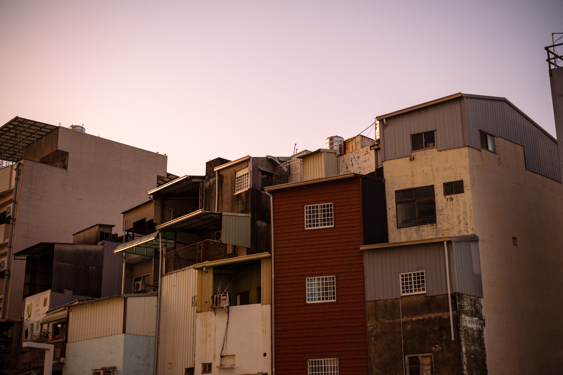 夕暮れ時、ホテルから外にでる。目の前に積み重なるように建物が立ちはだかる。かなり暗いが、開放値からほんの半絞りだけ絞って撮影。緩やかなトーン。こんな時間帯でも手持ちでも十分にいける<br><span class="fnt-85">ニコン Z7II／ZEISS Otus ML 1.4/50／50mm／マニュアル露出（F1.8、1/200秒）／ISO 400／WB：晴天</span>