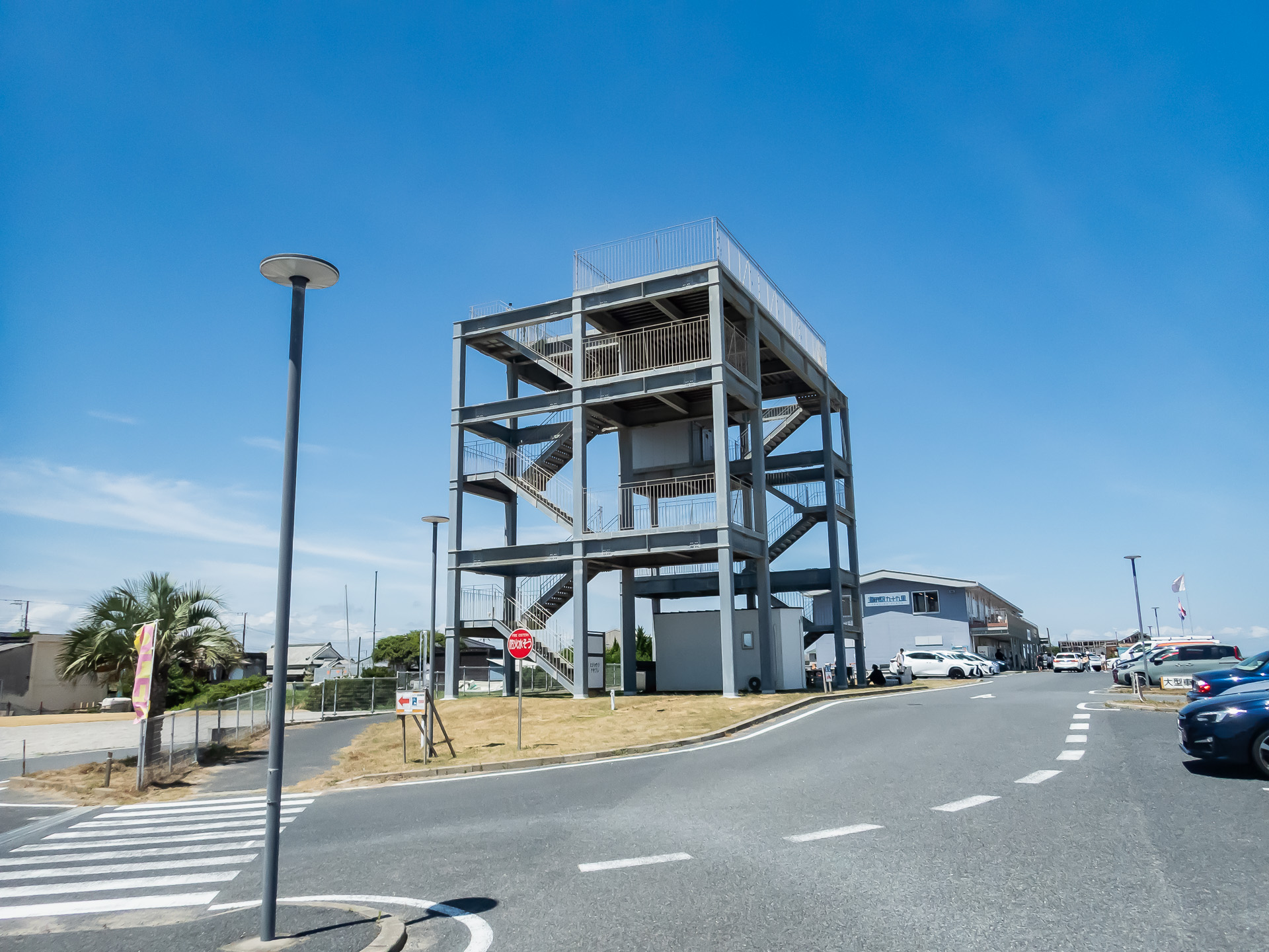 このちょっと不思議なスケルトンな建物、津波避難タワーです。津波や浸水の恐れがある場合に一時的に避難するものです。九十九里に限らず津波による浸水が予測される地域には全国的に設置されています。夏は海に遊びに行く機会も増えると思います。いざという時に備えてお出かけ前に場所を調べておきましょうね。写真の場所は片貝漁港にある「<a href="https://uminoeki99.com/">海の駅九十九里</a>」に併設された津波避難タワー。遠くからでも目立ちます。海の駅九十九里にはフードコート、資料館のほか海産物の直売所があり、片貝漁港で採れた魚介類や近辺の農家直送の野菜を買うことができます。どちらもお安くて新鮮！ この夏、海水浴ついでに立ち寄ってみてください。あ、クーラーバック持って行くといいかも！