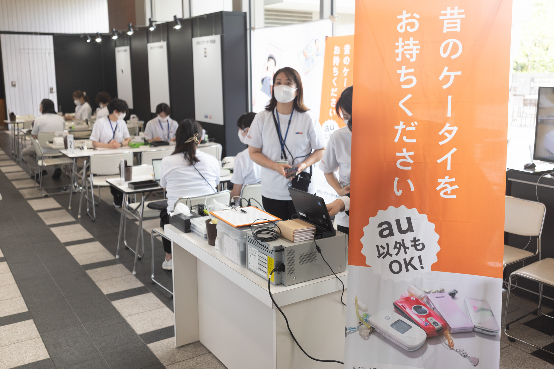 電源が入らなくなった携帯電話を再起動して端末の写真をプリントするKDDIのコーナー