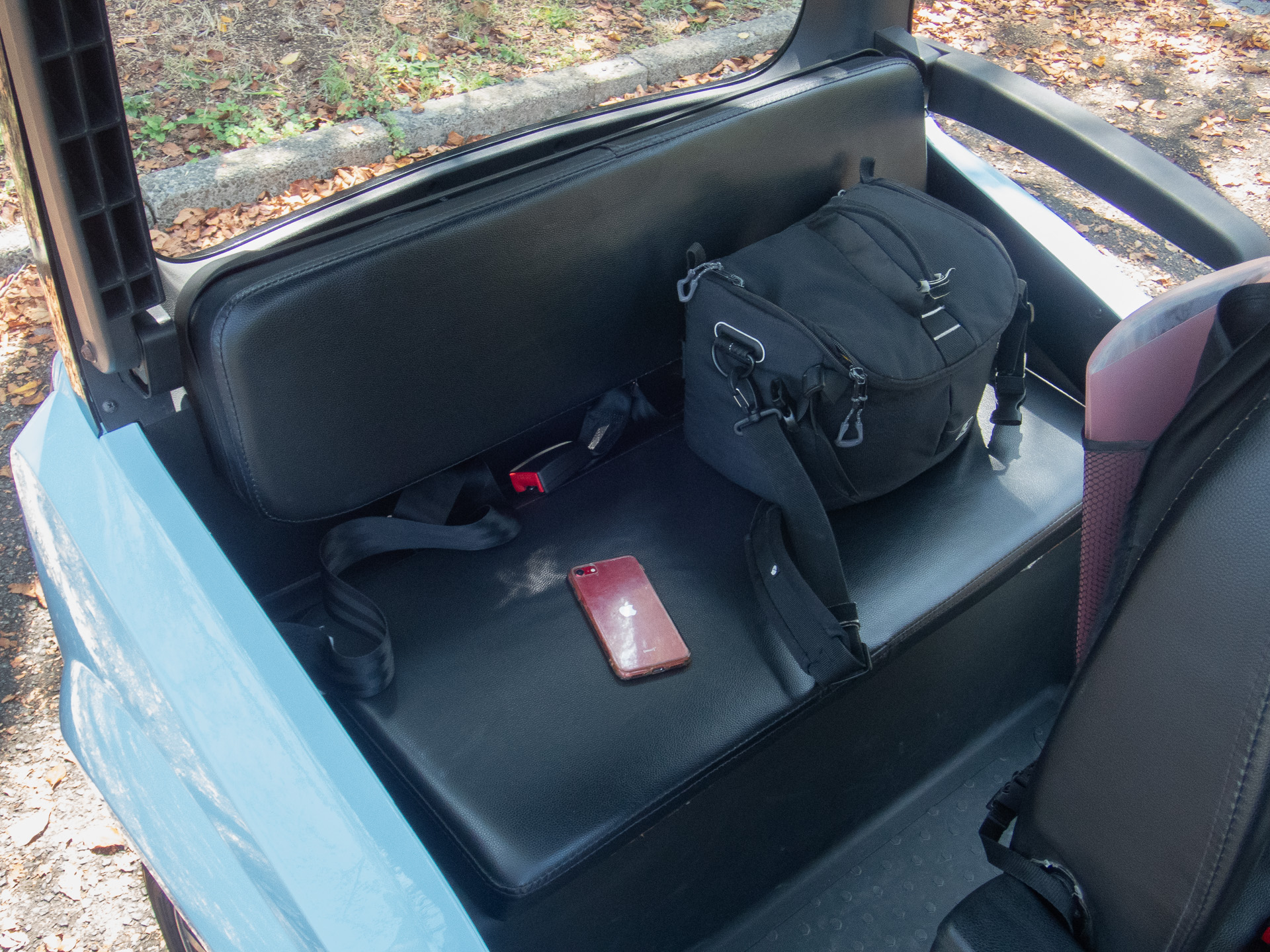 リアシートにカメラバッグを載せた。シートベルトで固定すれば走行もOKだ。赤いのはiPhone。大きさの比較のために置いてみた