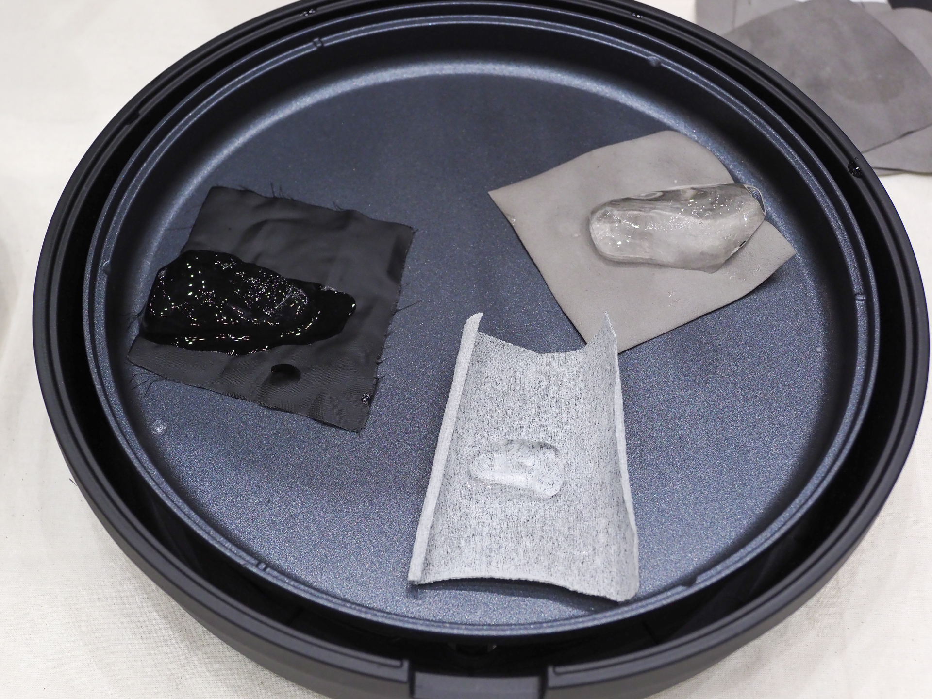 ホットプレートに生地を置いて、その上に氷を乗せて溶け具合を比較する実験。左の一般的な生地はすぐに氷が解けてしまうが、中央の断熱α、右の断熱βは氷が溶けにくい