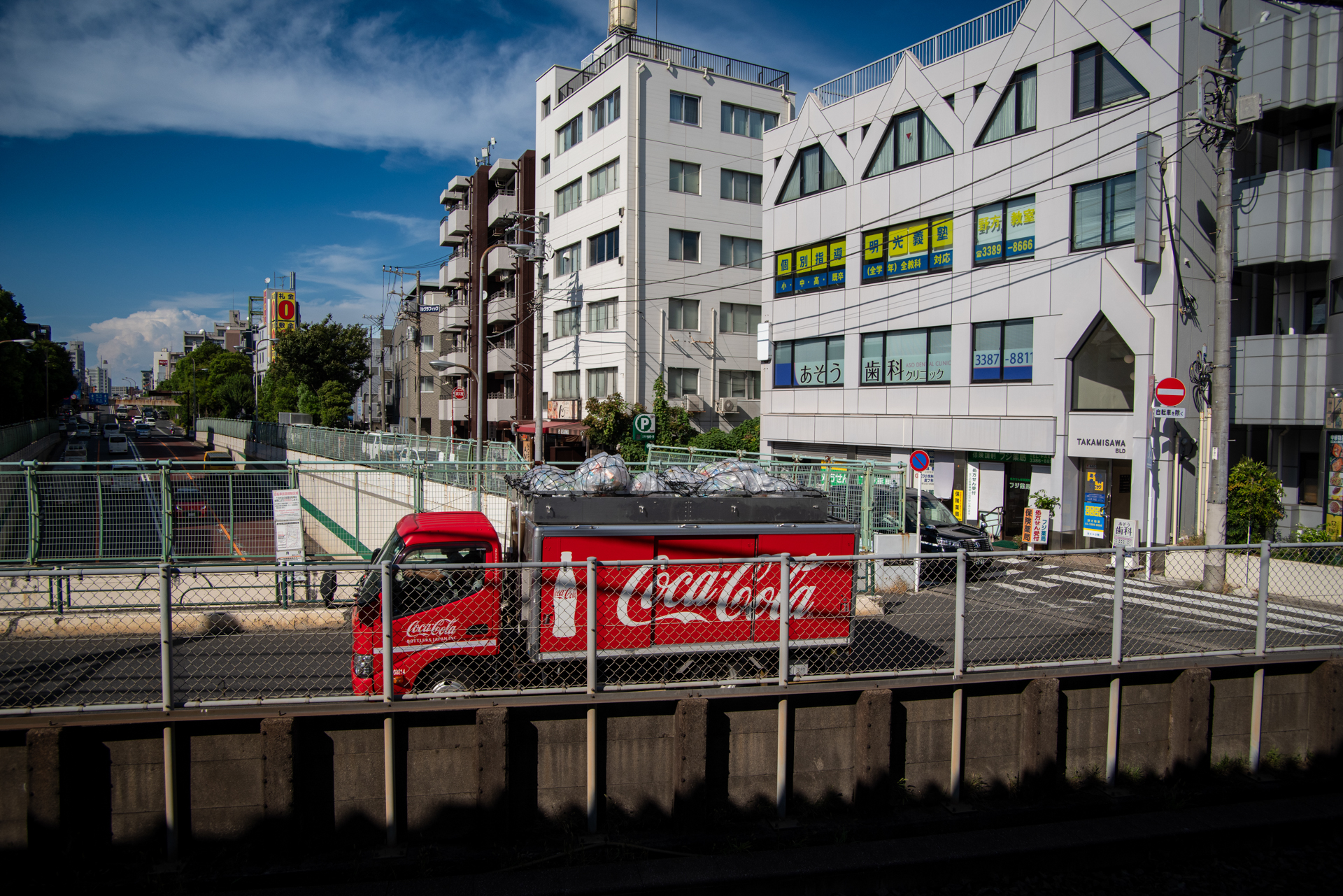 今月のコカコーラです。目の前に現れればシャッターを押してしまいます。車体の赤の再現いいですね。今年の夏は暑いけれど、青空は綺麗に出るようです。遠くの細かいところまで解像しています。<span class="fnt-85">PENTAX K-1 Mark II／smc PENTAX FA20-35mm F4／24mm／絞り優先AE（1/1,000秒、F8.0、−0.7EV）／ISO 400</span>