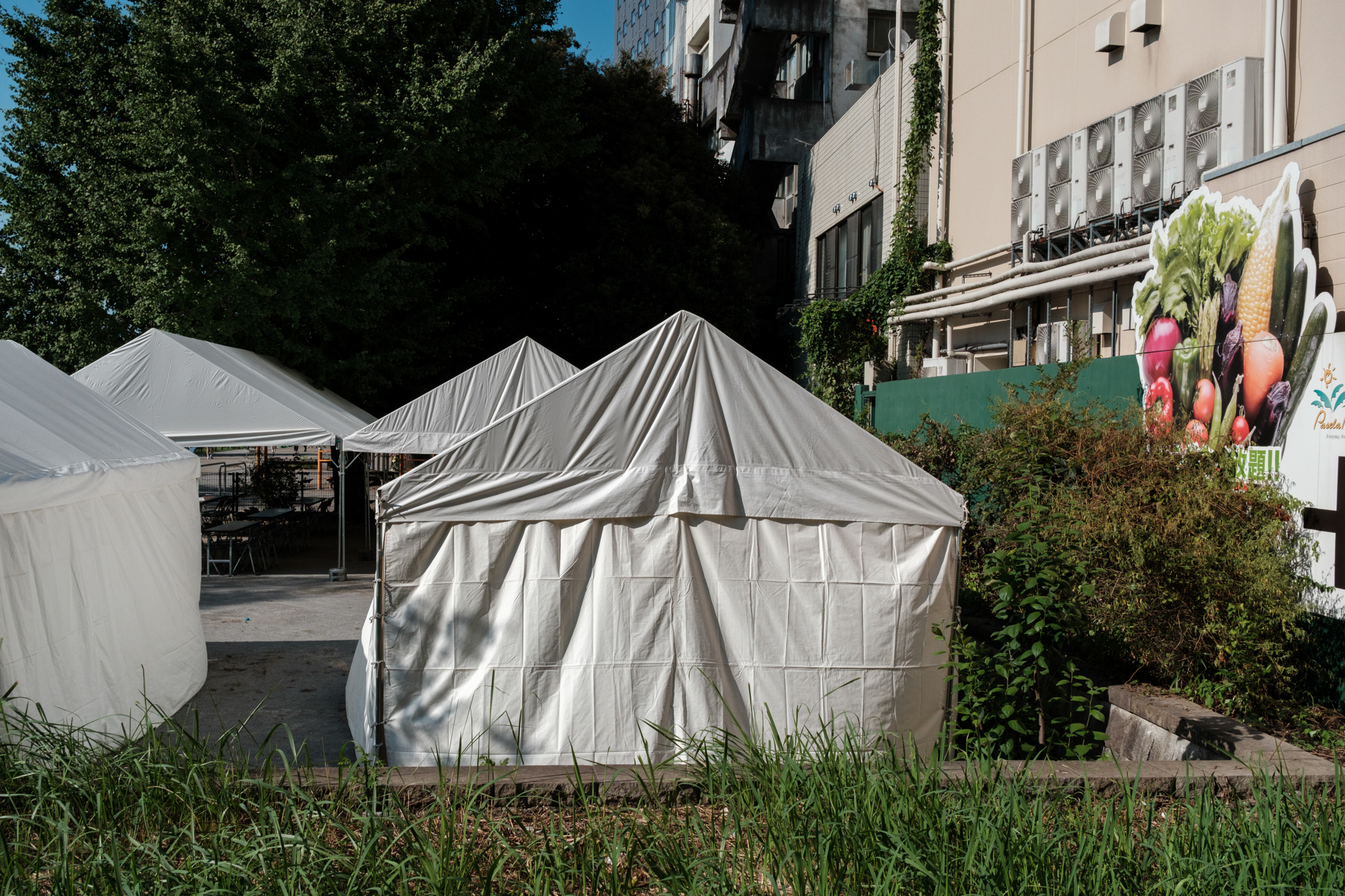 仮設テントの並ぶ空き地。こうした光景も非日常なわけで、不思議な雰囲気になりました。渋い雰囲気を期待してクラシッククリームを選びました。<br><span class="fnt-85">富士フイルム X-E5／XF23mmF2.8 R WR／23mm（35mm相当）／絞り優先AE（1/2,000秒、F8.0、−0.7EV）／ISO 400／フィルムシミュレーション: クラシッククローム</span>