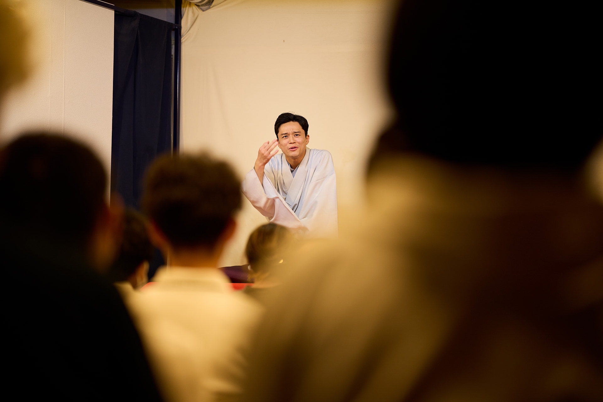 客席後方から高座を狙う。観客の存在を伝えつつ、噺家のじゃまになってはならない。このような場面で85mmとF1.4という組み合わせは、その場の熱量を伝えるのに有効だ<br><span class="fnt-85">キヤノン EOS R5 Mark II／85mm／マニュアル露出（F1.4、1/200秒）／ISO 400／WB：オート</span>