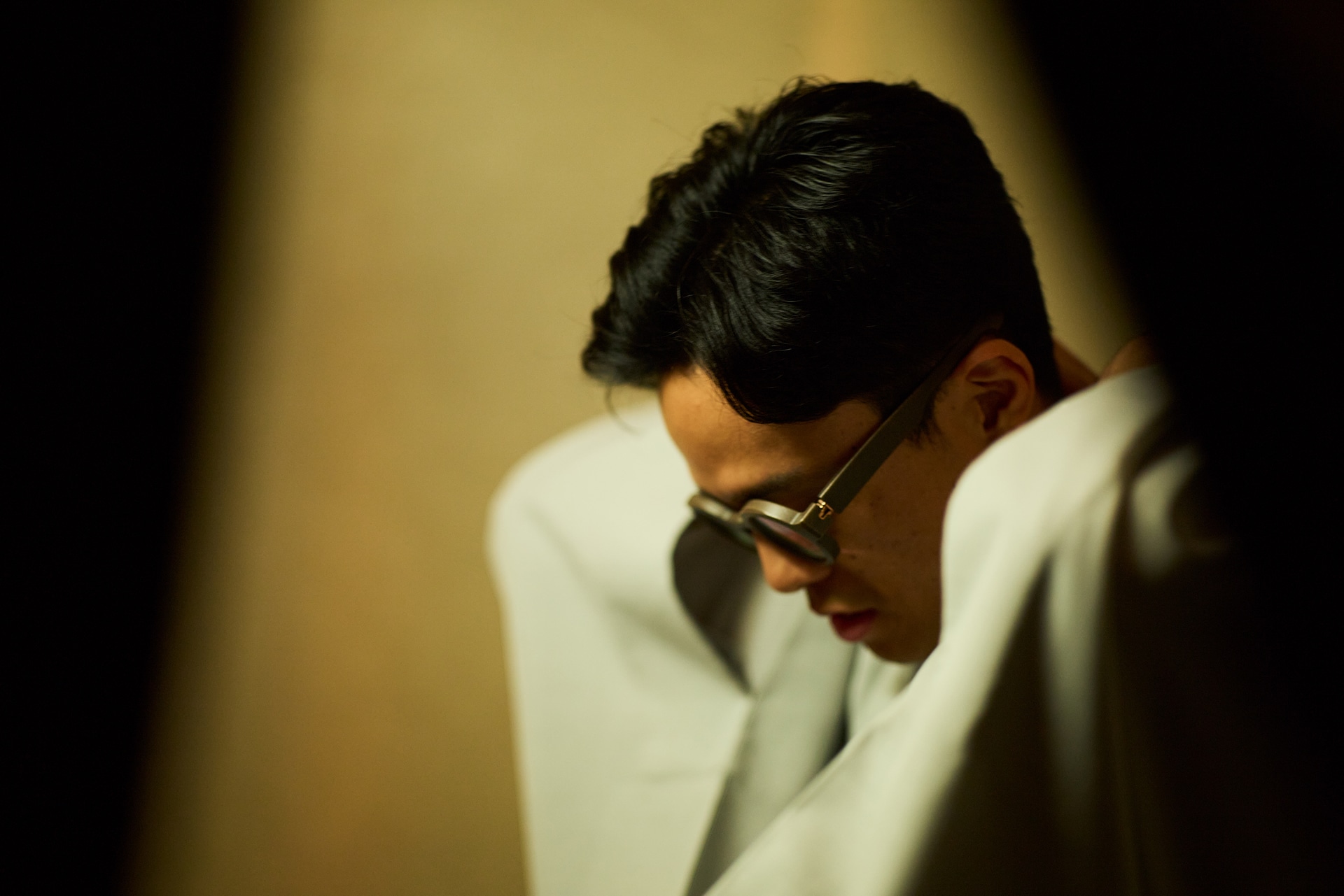 85mmによる圧縮効果とF1.4による浅い被写界深度による前ボケで表情に迫る。しっとりとした色彩描写が彼の雰囲気と合っている。高座に上がる直前の緊迫感を閉じ込めた<br><span class="fnt-85">キヤノン EOS R5 Mark II／85mm／マニュアル露出（F1.4、1/200秒）／ISO 800／WB：オート</span>