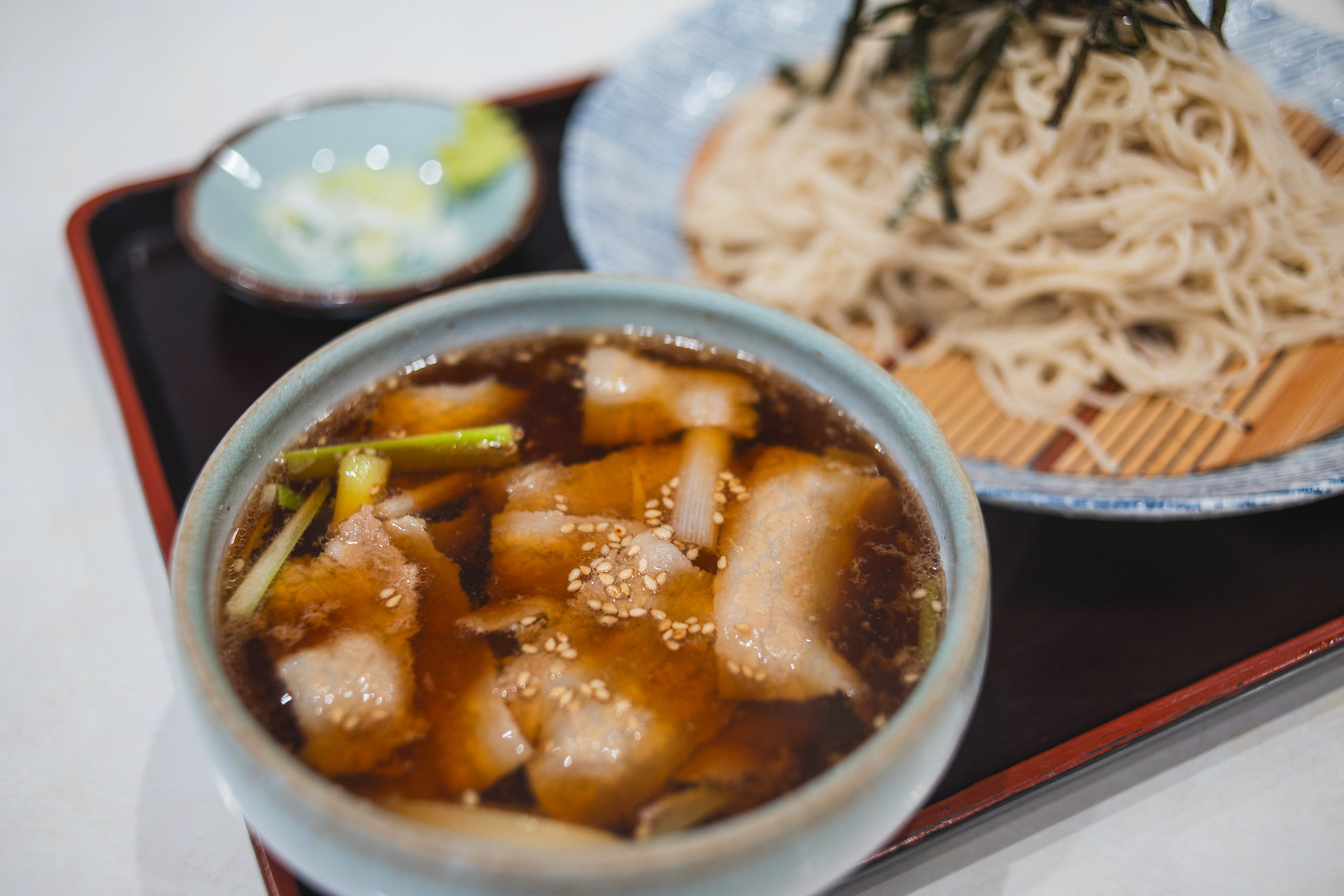 肉つけそば。広角レンズ特有のパースペクティブを絞りを開いたことで少々ごまかしてやろうという試みです。筆者はなにも指示していませんが、オートエリアで手前のつけ汁のゴマに合焦しました。<br><span class="fnt-85">ニコン Z5II／AF NIKKOR 35mm F2 D（LA-FZ1を使用）／35mm／絞り優先AE（1/100秒、F2.8、−0.7EV）／ISO 400</span>