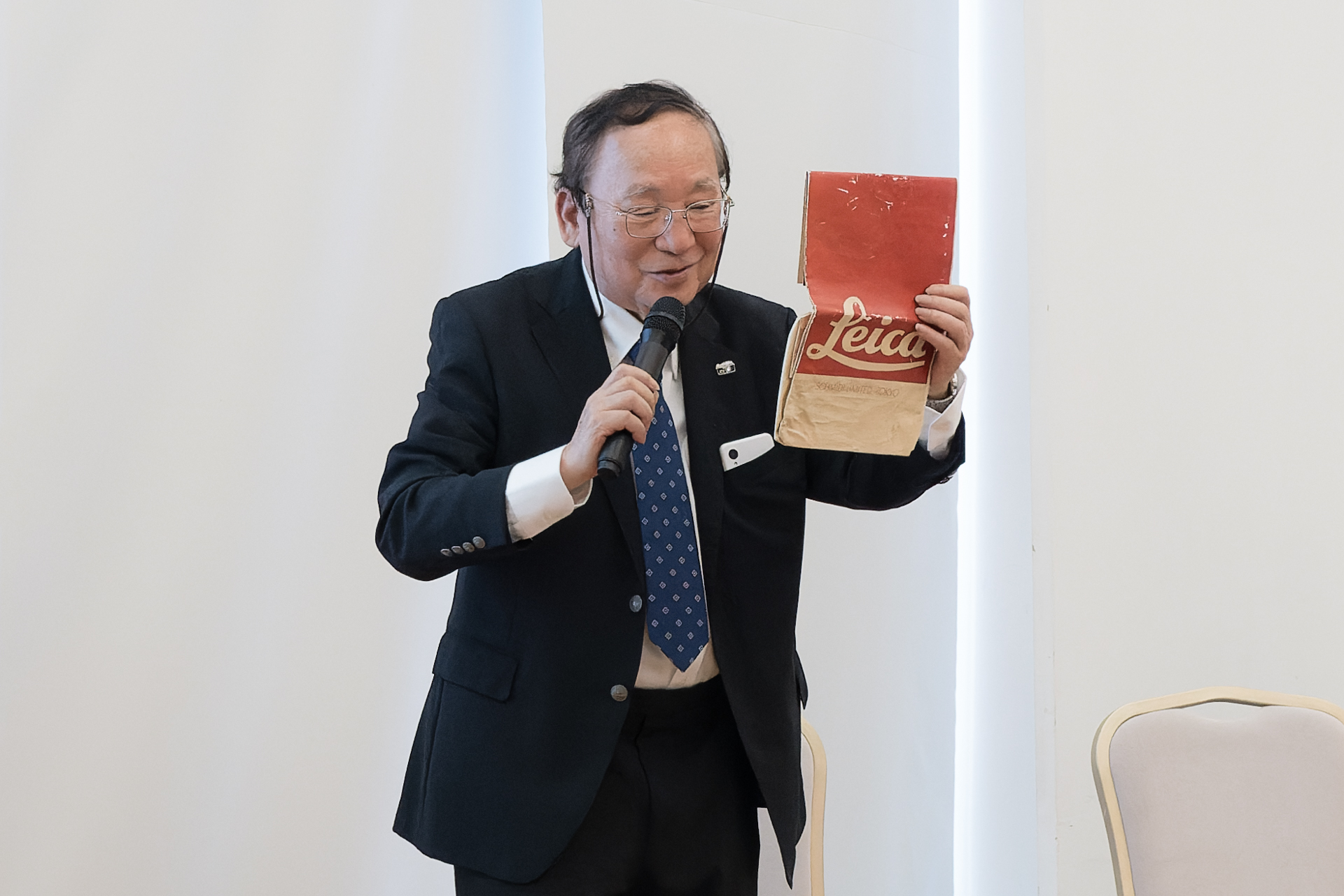 市川泰憲氏。ライカM3の箱にかかっていたという“シュミット”の文字が書かれた包装紙を示す