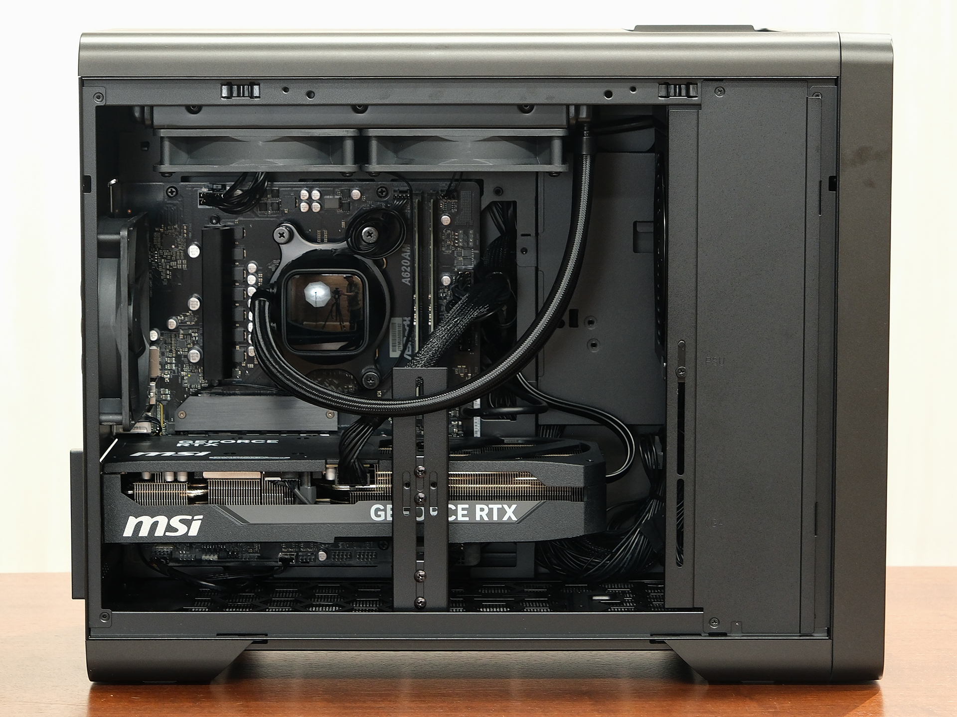 ミニタワー型PC「DAIV」の内部構造。下部の白文字のパーツが大型のグラフィックボード。天面には水冷用の2連ファン、背面（向かって左側）にも排気用のファンを搭載。右側にもファンが隠れている