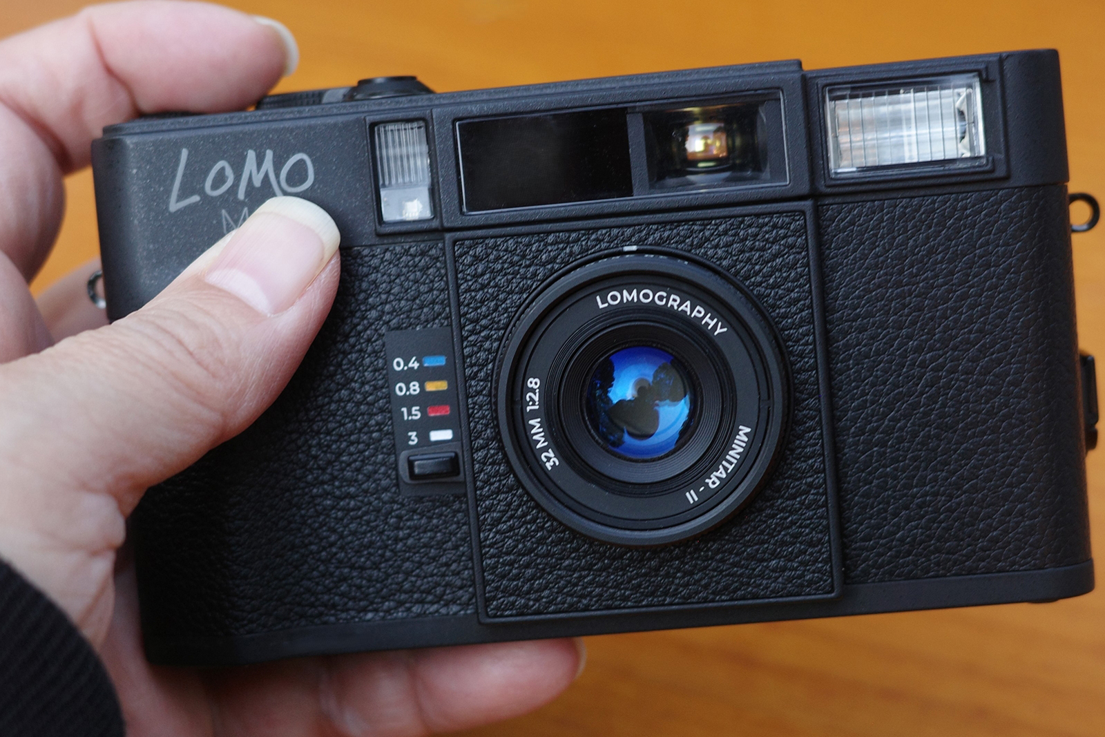 ゾーンフォーカス設定レバーは、0.4/0.8/1.5/3m/無限遠の5段階に設定できます。カラフルな撮影距離指標がロモらしい