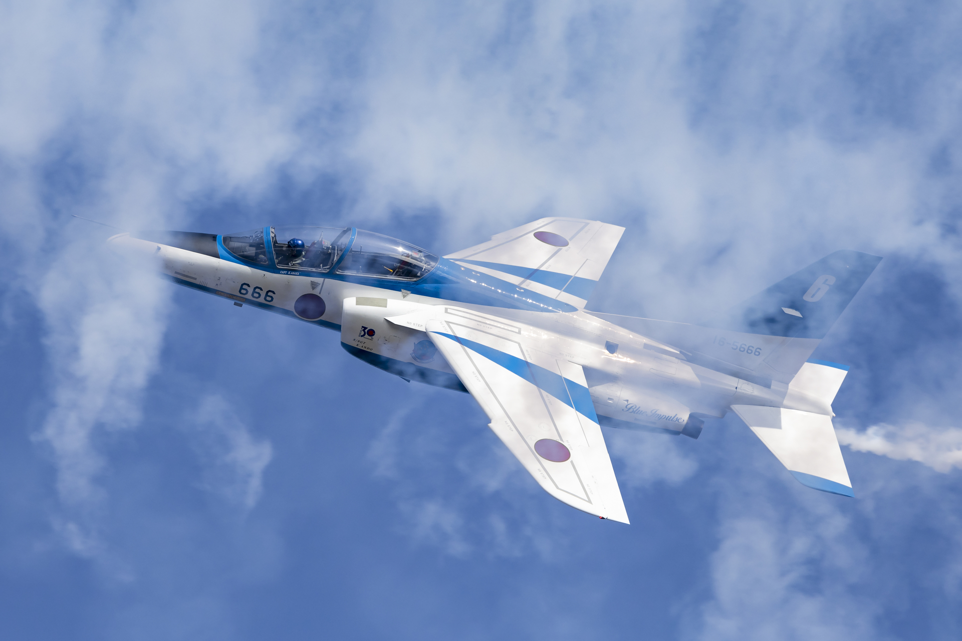 ブルーインパルスの課目『コーク・スクリュー』の６番機、課目の最後に旋回しながらスモークを引く５番機を追うシーン。スモークの合間から覗くコックピットと操縦する浅香１尉をしっかりと捉えています。<br>キヤノン EOS R6 MarkⅡ／RF100-500mm F4.5-7.1 L IS USM／500mm／シャッター速度優先AE（1/2,500秒、F8.0）／ISO400