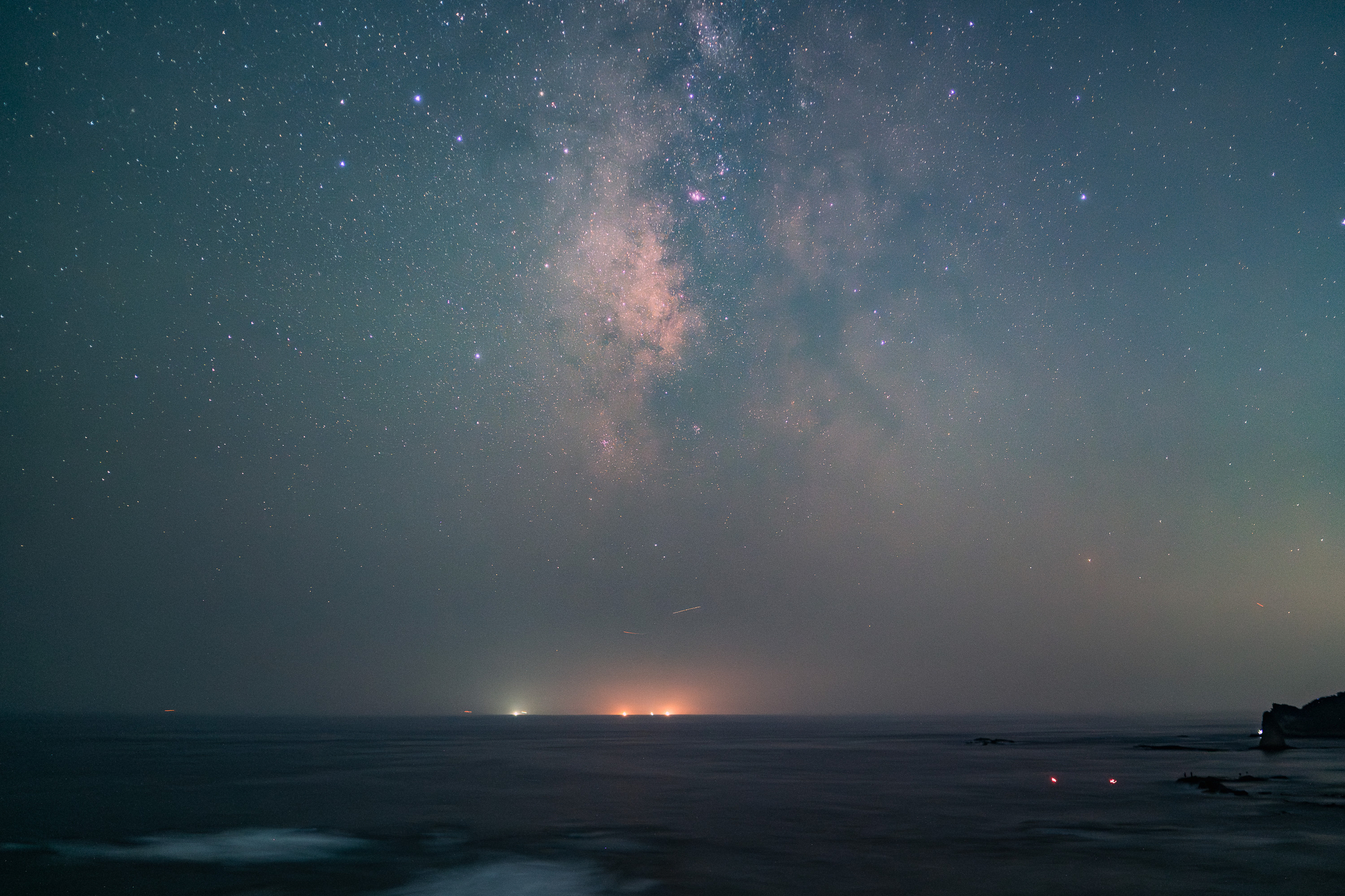 海上に浮かぶ夏の天の川中心部。赤い星雲M8やいて座の星の並び、入り組んだ天の川の暗黒帯がよく写っている。晴れ間を狙って手軽に撮影できるのはフォーカスメモリーのおかげだ。星景写真で一番手間のかかる作業が省略できるのだ<br>ソニー α7C／SAMYANG VAF 35mm T1.9／35mm／マニュアル露出（20秒、F2.5）／ISO 4000