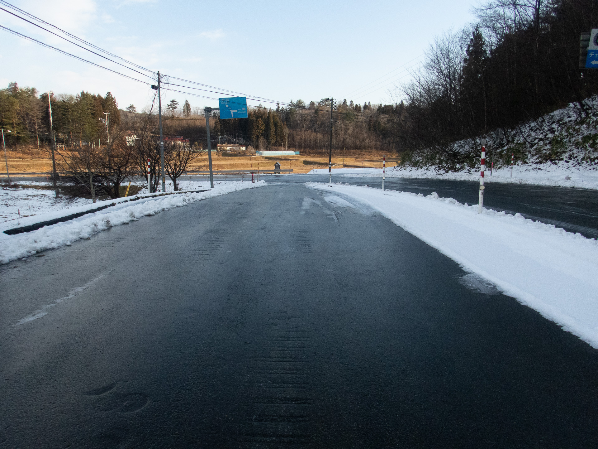 ゆるい下り坂のチェーン着脱場。ブラックアイスバーンになっている