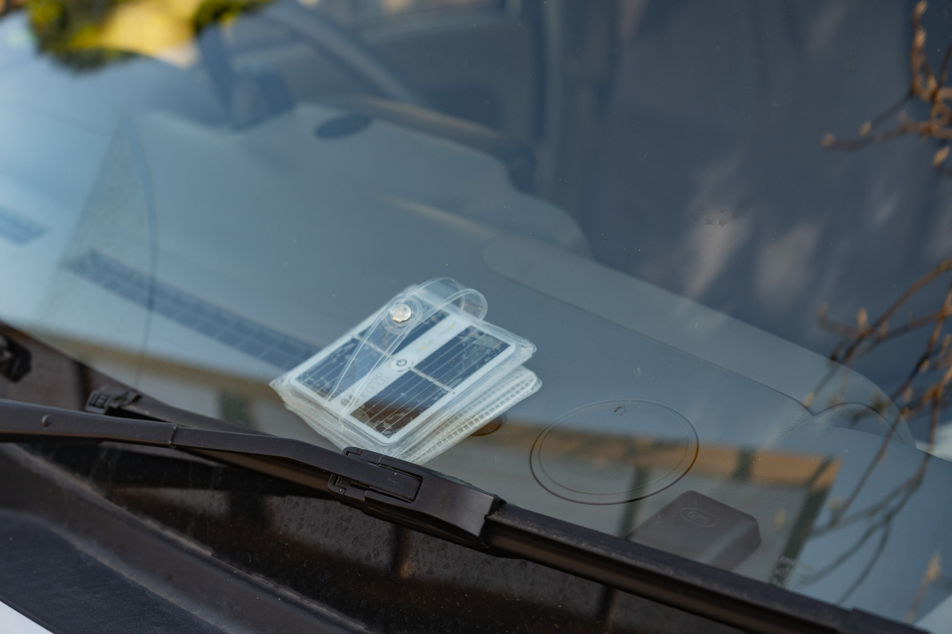 ダッシュボードで充電中。運転中は危険でもあるのでサイドウインドウやリアウインドウに貼り付けておくとよい。スイッチONにしていても、光が当たると自動的に消灯する