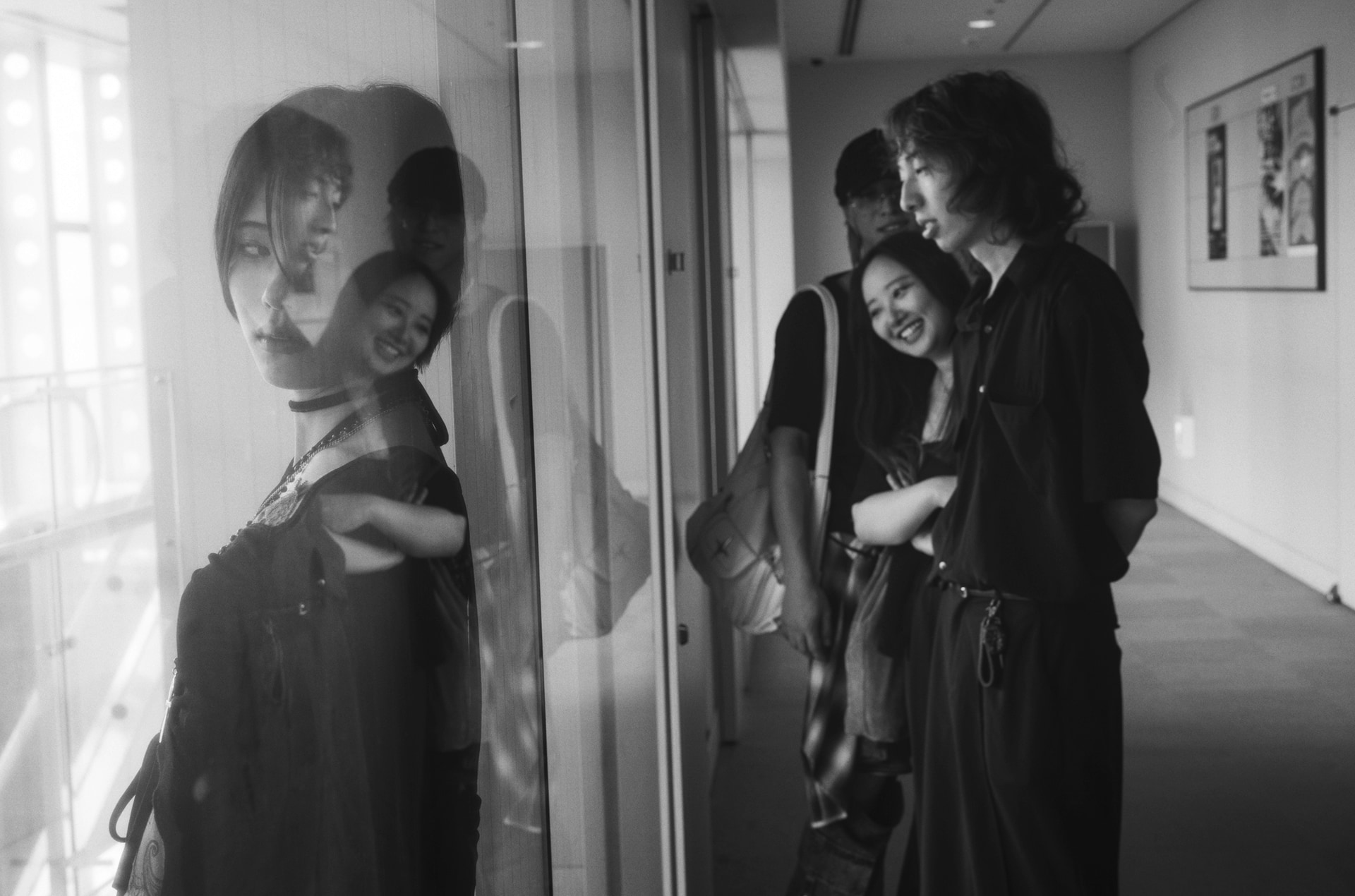 私が校長を務める日本写真芸術専門学校の姉妹校「日本デザイナー学院 九州校」でのカット。手前と奥がガラス張りになった廊下に学生たちを配置した。ガラスへの映り込みと、向こう側にいる人物が重なる「レイヤー（層）」の効果を意図的に狙っている。左の彼女には少し前後に動いてもらうなど、構図のバランスにもこだわった<br><span class="fnt-85">Leica Camera ライカM10モノクローム／ズミルックスM f1.4/50 ASPH.／50mm／マニュアル露出（F1.4、1/60秒）／ISO 800</span>