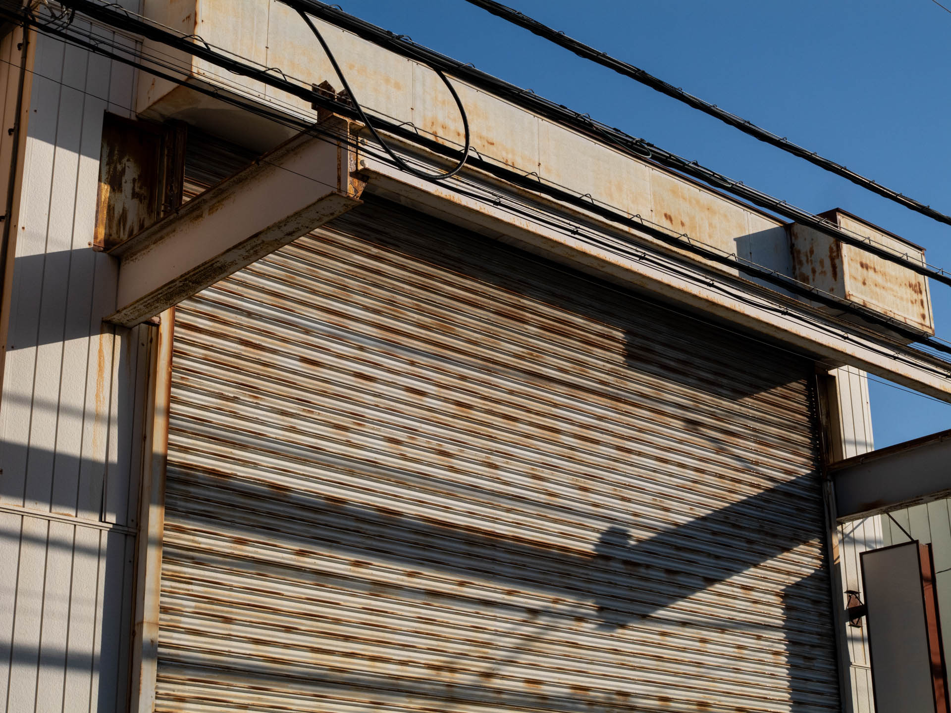 錆びたシャッターに青空とくれば、撮らないわけにはいきません。理由はないけど、見事な鮮鋭性です。<br><span class="fnt-85">LUMIX G9PROII／SIGMA 30mm F2.8 EX DN／30mm（60mm相当）／プログラムAE（1/2,000秒、F8.0、−0.7EV）／ISO 400</span>