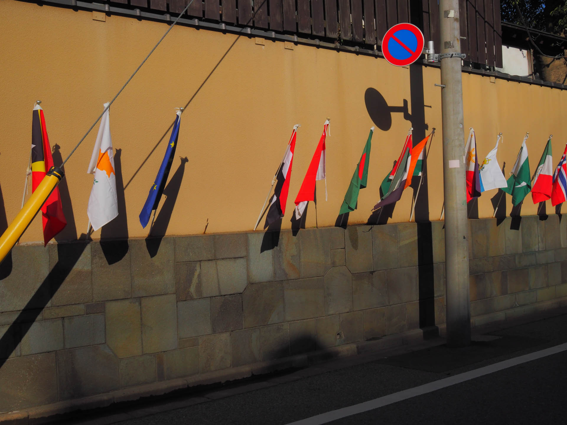 街の万国旗。なんだと思ったら、盆栽販売店でした。<br><span class="fnt-85">OLYMPUS PEN-F／SIGMA 19mm F2.8 DN／19mm（38mm相当）／プログラムAE（1/1,000秒、F11、−0.7EV）／ISO 400</span>