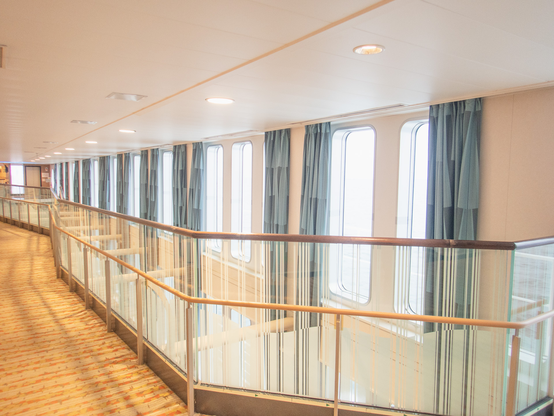 日中のプロムナードは窓から差し込む光で心地良い。夜は航行の安全のため、カーテン閉めるんですよ