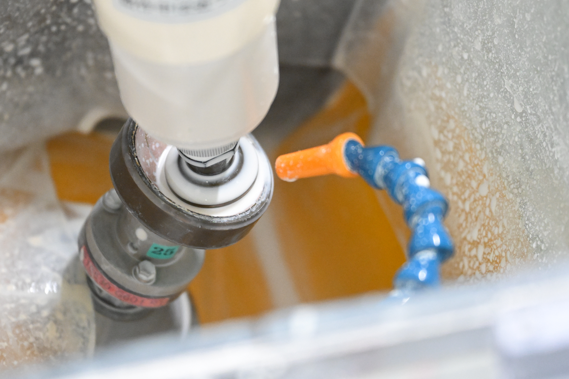 研磨中の様子。ホルダーに装着されたレンズが、下の研磨パッドに触れている。白色の研磨材を使っている