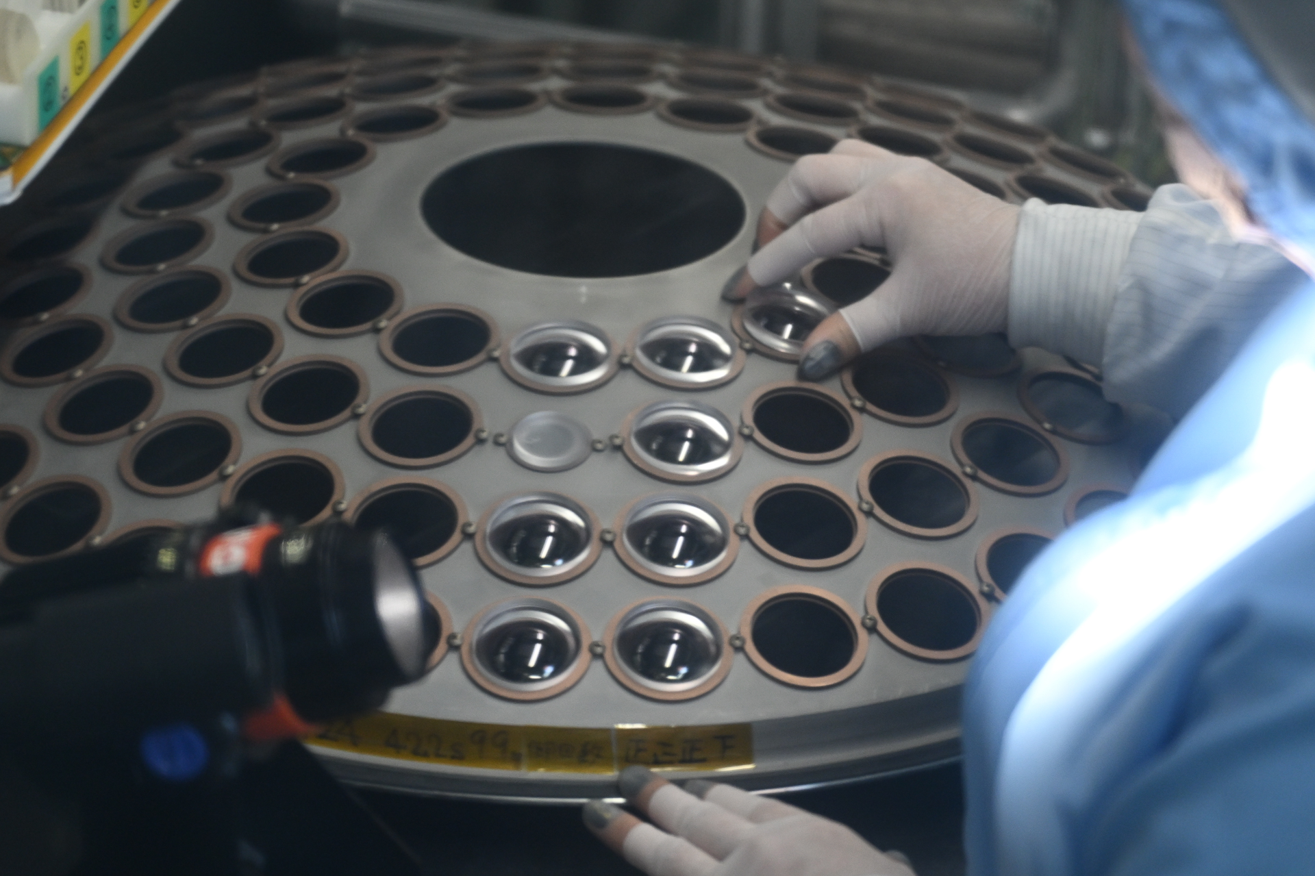 レンズをドームにセットしているところ。清浄度を保つ透明カーテン越しに撮影