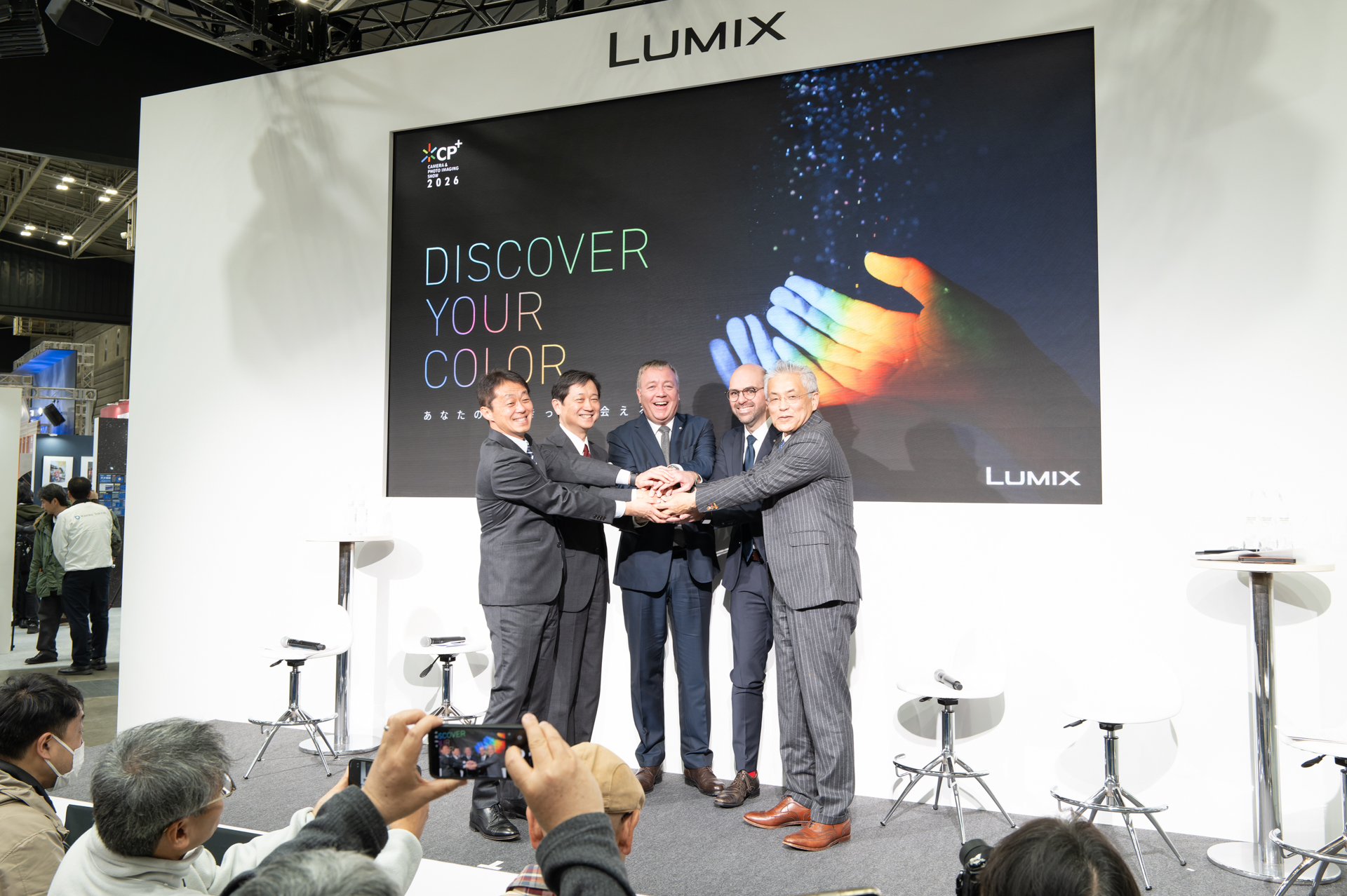 CP+2026初日のパナソニックブースにて。左からパナソニック津村敏行氏、シグマ大曽根康裕氏、ライカカメラ社ステファン・ダニエル氏、ヴァレンティノ・ディ・レオナルド氏、杢中薫氏。トークの締めにシグマ大曽根氏が「みんなで握手しませんか？」と提案し、フォトセッションに。集まった観客を大いに盛り上げた