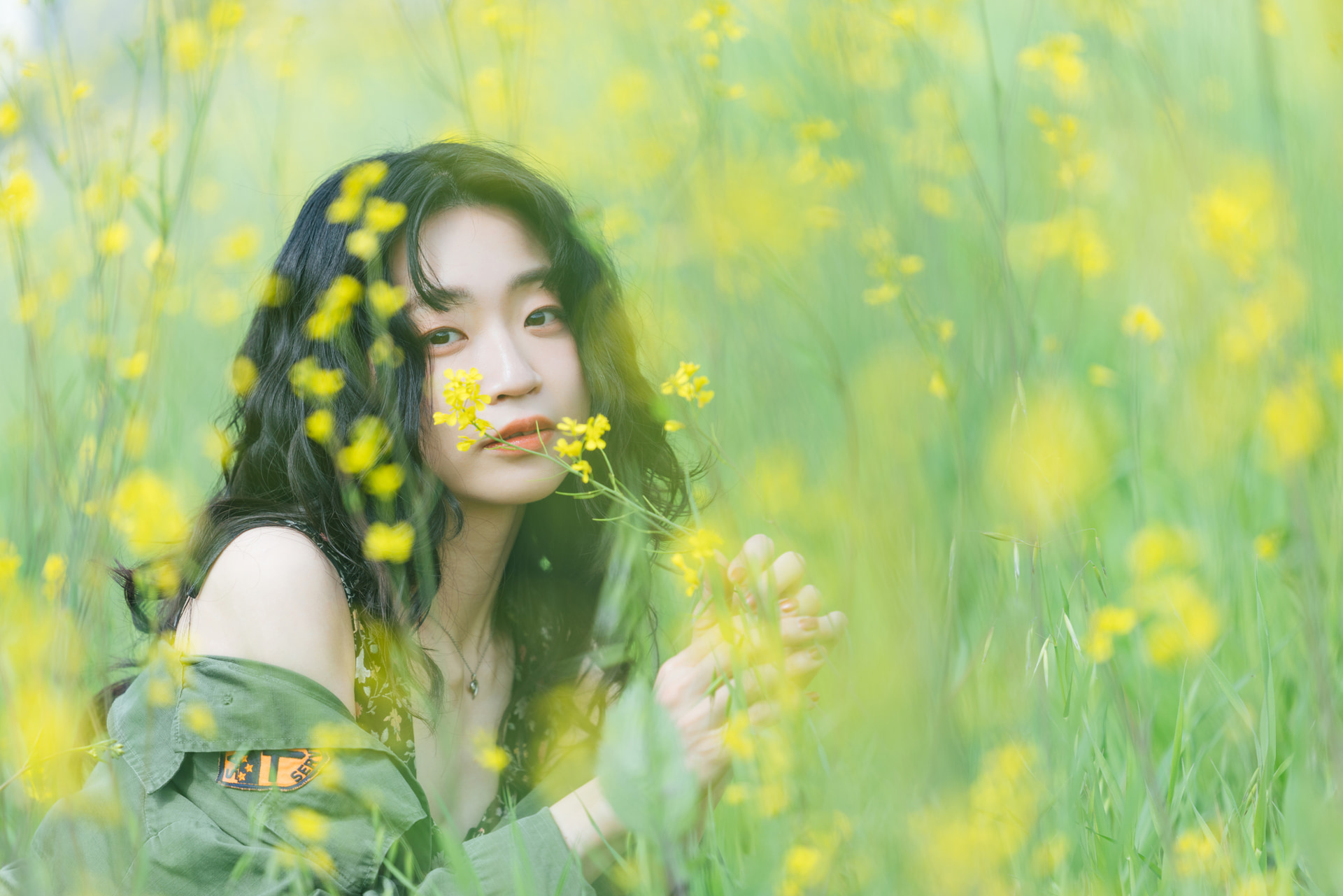 黄色い花に包まれた幻想的なイメージにするため、望遠レンズの開放F値に設定。局地的なスポットにしか咲いていなかったが、圧縮効果のおかげで花畑にたたずんだ様子を表現できた<br><span class="fnt-85">キヤノン EOS R5 Mark II／RF70-200mm F2.8 L IS USM／187mm／絞り優先AE（F2.8、1/1,250秒、＋0.7EV）／ISO 100／WB：オート</span><br>モデル：繭乃　ヘアメイク：川口陽子　衣装協力：HENAMA