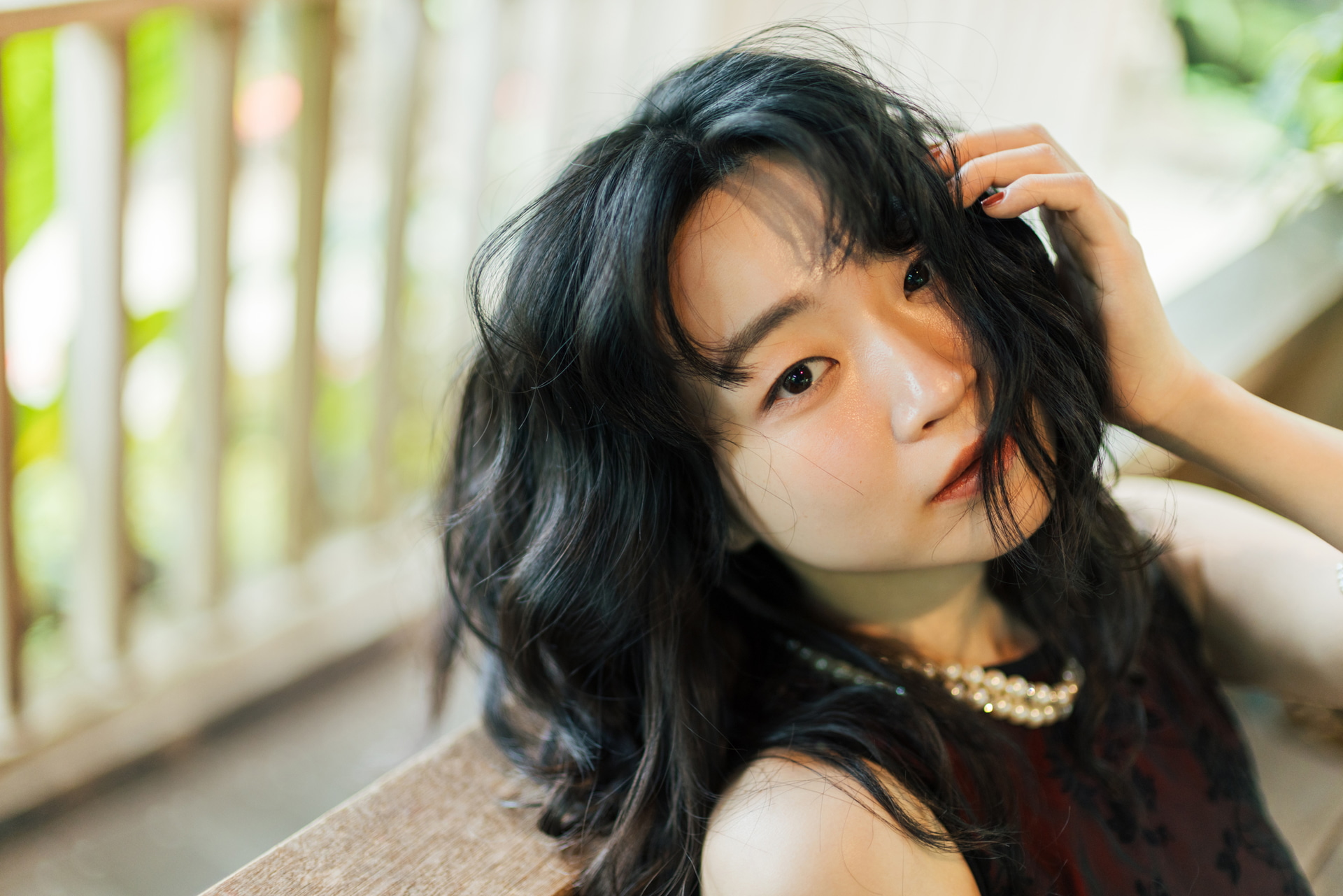 タングステン光の赤みがあったので少し艶っぽい肌のイメージを狙った。背もたれにもたれ掛かり、髪で片目を隠してもらっている。瞳検出の限定は右目優先にし、手前の右目にピントを合わせて浅い被写界深度で目力を強調した<br><span class="fnt-85">キヤノン EOS R5 Mark II／RF45mm F1.2 STM／45mm／絞り優先AE（F1.4、1/160秒、＋0.3EV）／ISO 500／WB：4,300K（B3,0）</span>