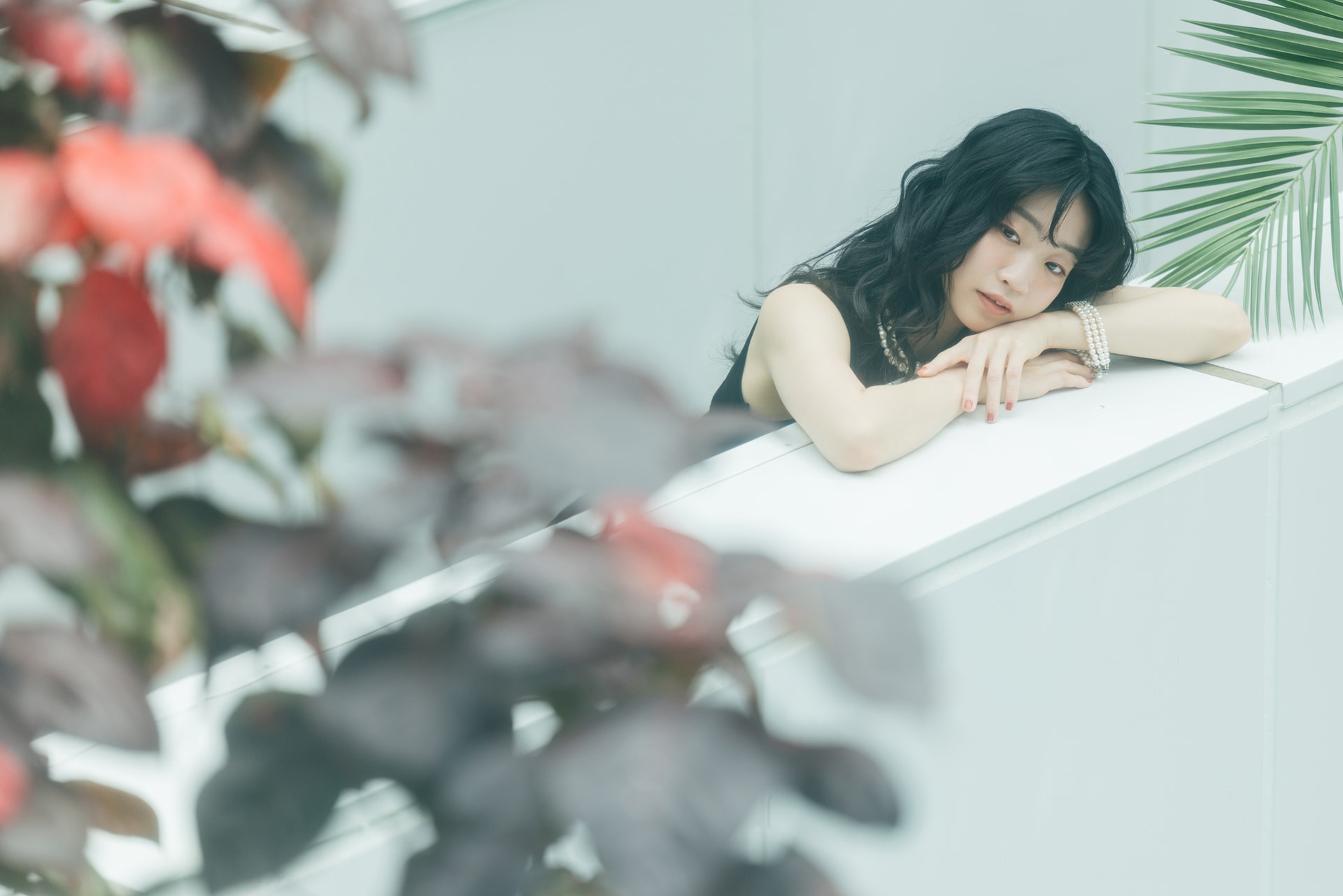 10mほど離れた場所からガラス越しにイノセントな雰囲気を目指した。ガラスでソフトフィルターのような効果をプラス。大きな葉のボケをアクセントに人物に目線を誘導している<br><span class="fnt-85">キヤノン EOS R5 Mark II／RF70-200mm F2.8 L IS USM／200mm／絞り優先AE（F2.8、1/320秒、－0.3EV）／ISO 100／WB：4,300K（B3,0）</span>