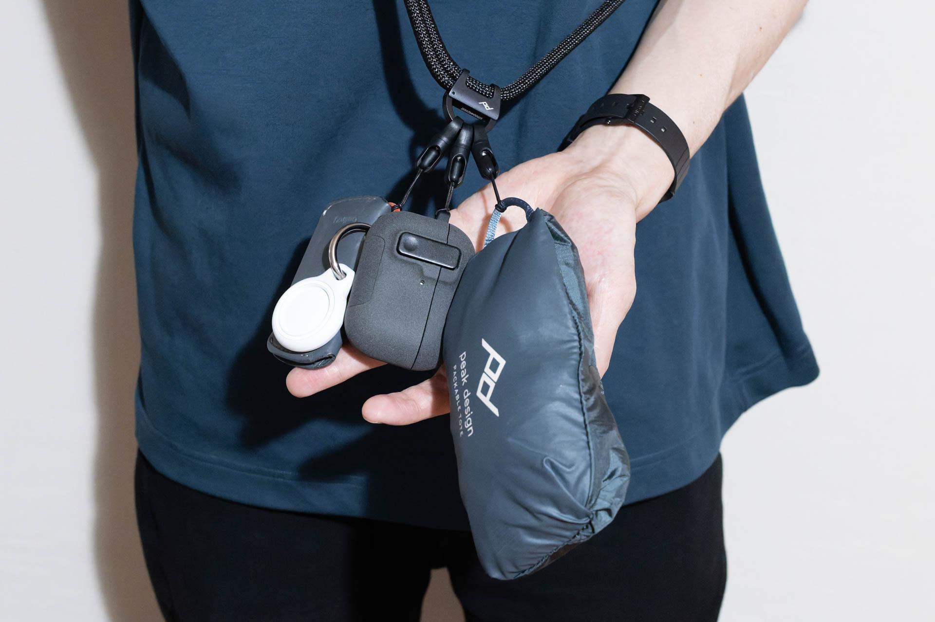 筆者の使用例は、左から「鍵（Bellroyのキーケース、BelkinのAirTagホルダー）」、「イヤフォン（AirPods Pro 3、ロック機構付きケース）」、「エコバッグ（Peak Designのパッカブル トート）」。一緒に取り付けているアイテム同士が触れ合うため、カメラの装着には気を使う印象