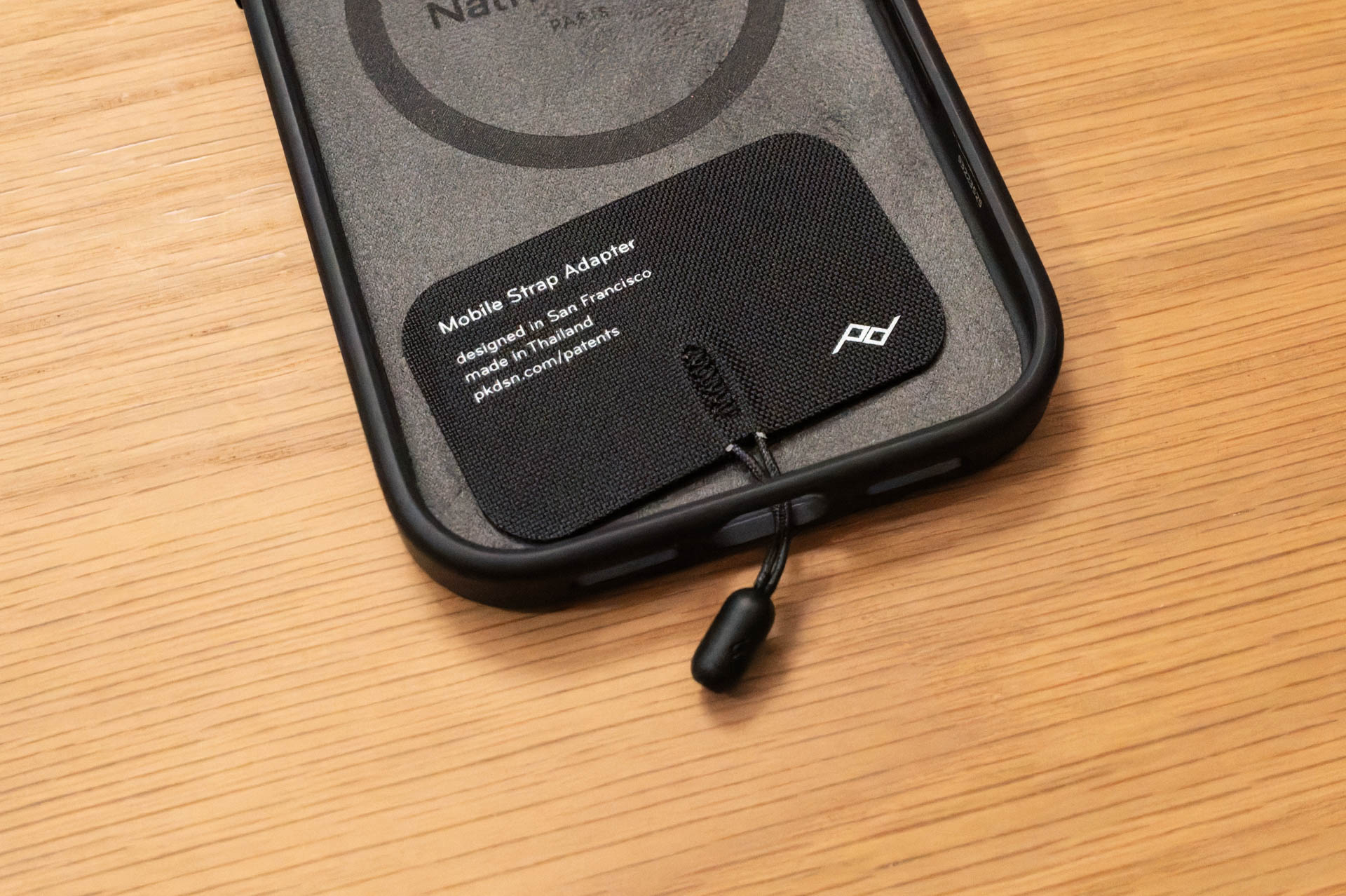 モバイル ストラップ アダプター。ケースの端子穴を使用する仕組み。Peak Designのスマホケースなら、ケースに直接マイクロアンカーを取り付けて2点吊りできる