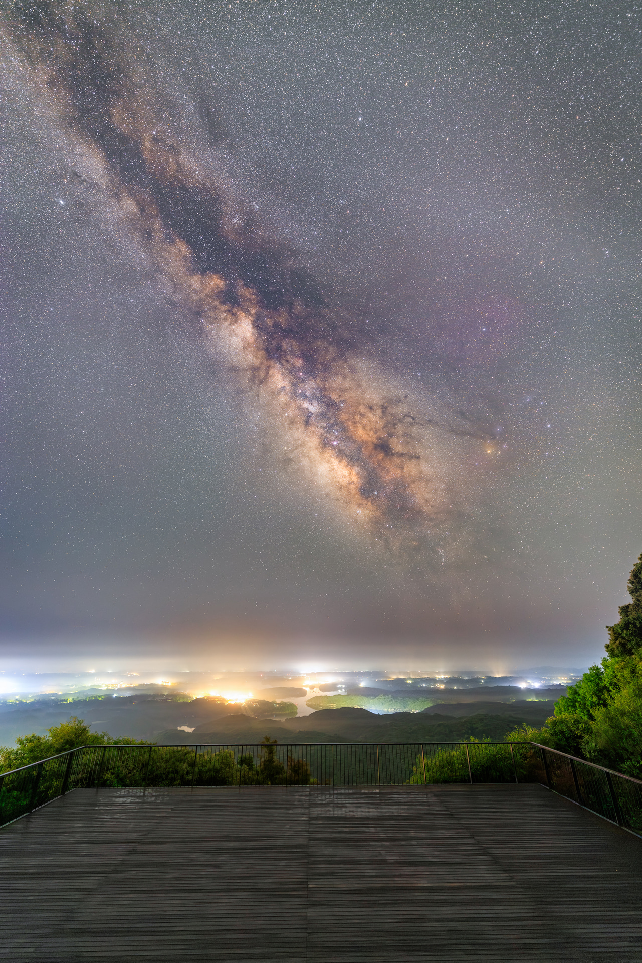 横山展望台から夜景と天の川をコラボ。かなりもやが濃かったものの、それが夜景の神秘性を高めてくれた。湿度が高く機材がぬれたが、高い防塵・防滴性能が心強かった<br><span class="fnt-85">キヤノン EOS R5 Mark II／14mm／マニュアル露出（F1.4）／WB：5,050K／107枚合成</span>