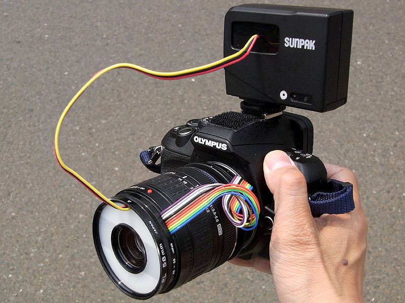 <b>完成したマクロストロボを、「リバースマクロ14-42mm」と共に「E-420」に装着してみた。2灯式の発光部が、58mm径のフィルター枠の中に収められているわけで、マクロ用ストロボヘッドとしてはまさに最小最薄ではないかと思われる</b>