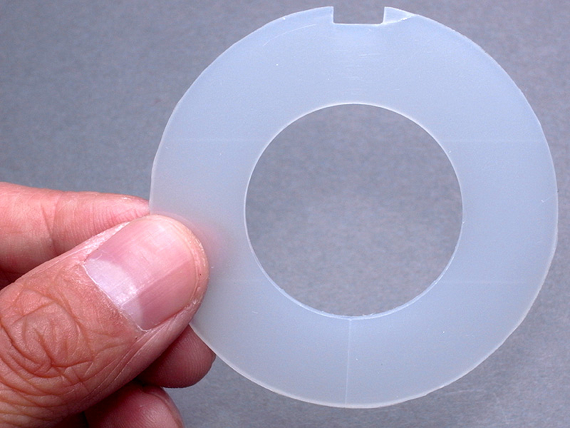 <b>1mm厚の乳白色アクリル板から、このような形状のパーツを切り出す（円形のカットの仕方は前回の記事を参照）。パーツにヒビが入ってしまったが、アクリルは割れやすい素材で加工もしにくいため、このまま使用することにした。パーツの外径は、58mmフィルターガラスの大きさに合わせている</b>