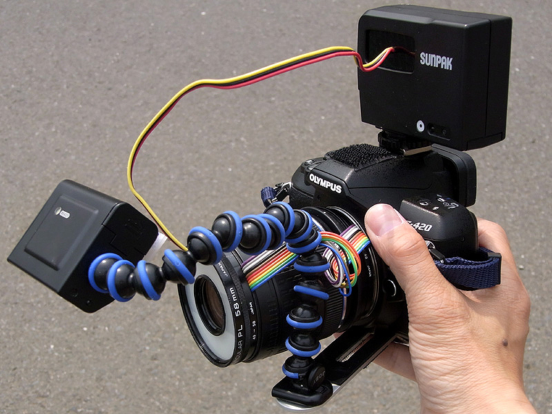 <b>逆光用スレーブストロボをカメラに装着するとこんな感じ。レンズのワーキングディスタンスは約4cmなので、ストロボはだいたいこんな位置にセットされる。高倍率マクロシステムとしては非常ににコンパクトで、手持ち撮影も楽に行なえる（と言っても基本的に大変な撮影なのだが）。しかし配線だらけの外見はいかにも怪しげで目立つ</b>