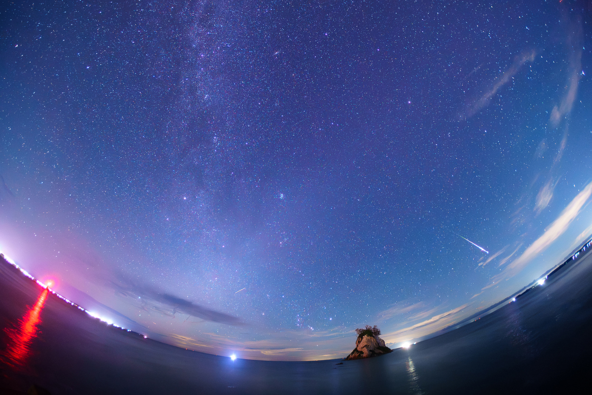 能登半島・見附島を望む海岸で撮影。ペルセウス座流星群の極大日、雲の切れ間を狙った。流星がどこに現れても捉えやすい魚眼の広い画角が生きた<br><span class="fnt-85">ソニー α7S III／10mm／マニュアル露出（F2.5、15秒）／ISO 6400／WB：冷白色蛍光灯</span>