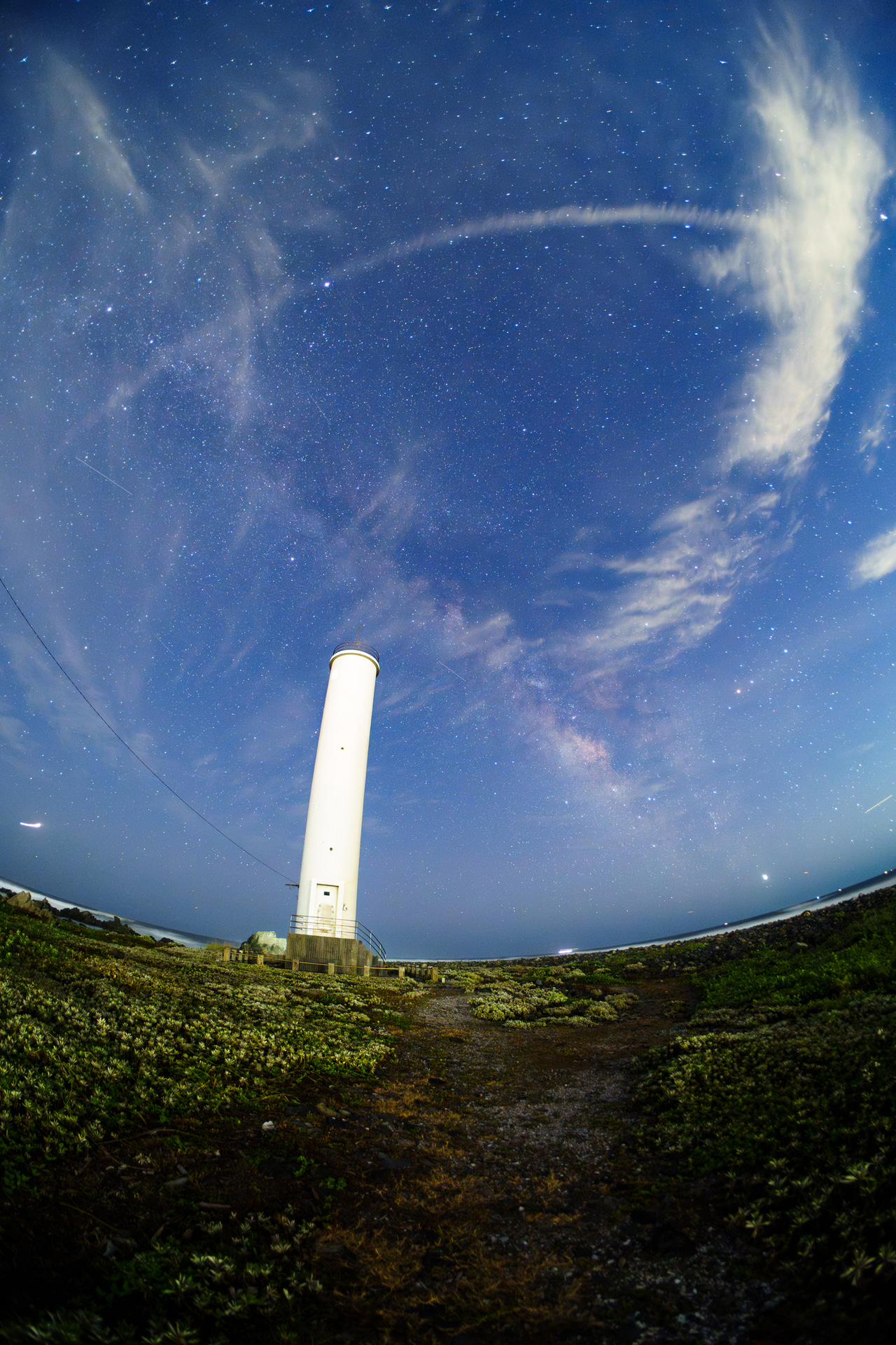 千葉県で灯台と夏の天の川を縦構図で撮影。銀河系中心部から夏の大三角まで収めつつ、縦に伸びる灯台の存在感を魚眼の広い画角で強調した<br><span class="fnt-85">ソニー α7 IV／10mm／マニュアル露出（F2.5、15秒）／ISO 4000／WB：マニュアル</span>