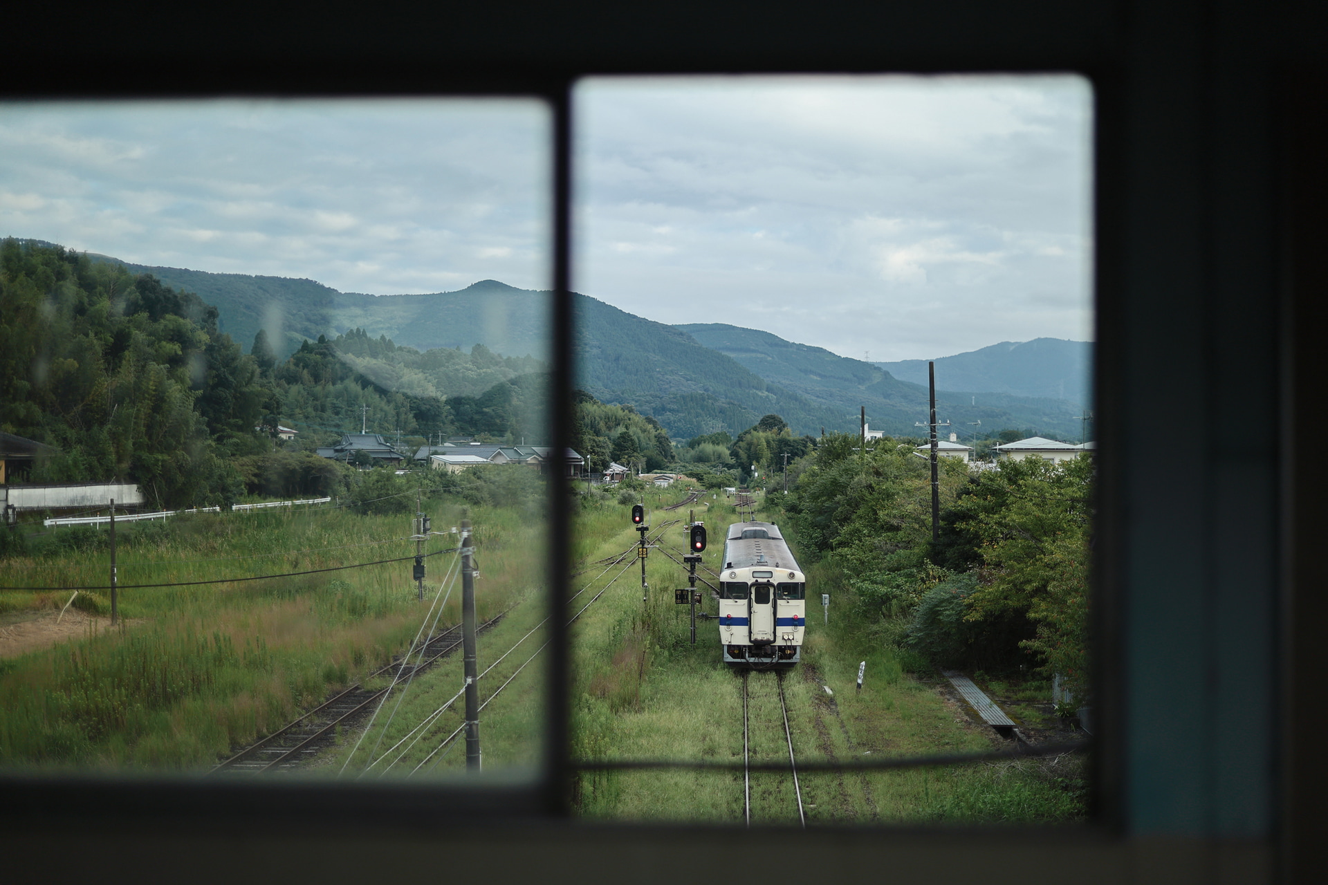 出発する列車が跨線橋の窓ごしに見える旅の道中。窓枠を額縁にPositiveFilmtoneを選び印象的に捉えた<br><span class="fnt-85">キヤノン EOS R8 Mark II／RF45mm F1.2 STM／45mm／マニュアル露出（F1.2、1/640秒）／ISO 125／WB：オート／JR吉都線</span>