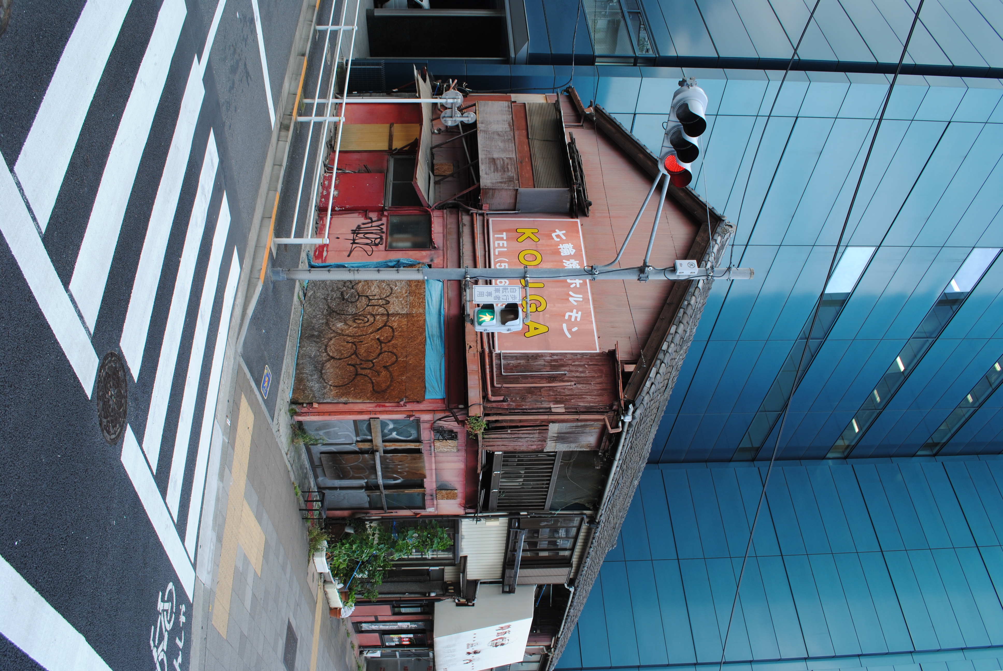 <b>えらくハイテクそうなビルに囲まれるかっこうで残っている住宅兼店舗（営業はしてないっぽい）。なんだかとてもドラマチック<br>AF-S DX NIKKOR 18-55mm F3.5-5.6 G VR / 3,872×2,592 / 1/40秒 / F8 / -0.3EV / ISO100 / WB:晴天 / 18mm</b>