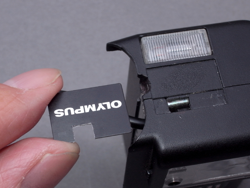 <b>スイッチつまみがスライドできるよう、A11の前カバーの一部を削る。「OLYMPUS」のネームプレートも、ご覧のように一部をカットする</b>