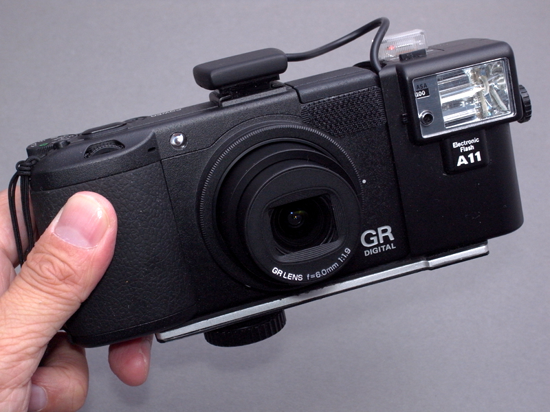 <b>改造したA11を、ためしにリコー「GR DIGITAL III」に装着してみたところ、これがピッタリだった。GR DIGITAL IIIは、ある意味XAの血を濃く受け継いでいるといえるから、当然かもしれない。ただし、GR RIGITAL IIIはストロボを内蔵しているから、A11を装着する必然性はない（笑）</b>