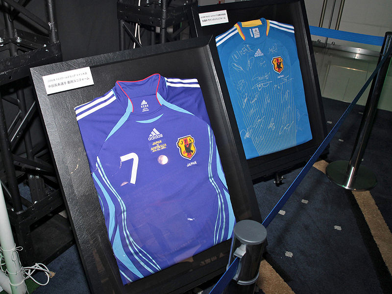 <b>中田英寿選手がFIFAワールドカップ（2006年ドイツ大会）で着用したユニフォーム（手前）なども展示していた。奥は2010年FIFAワールドカップ出場選手全員のサイン入りユニフォーム</b>