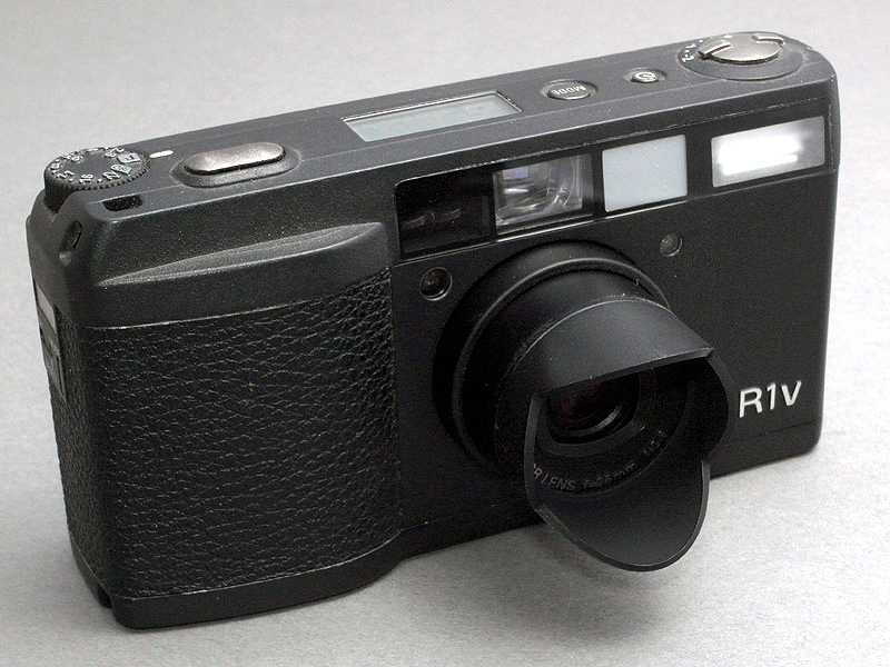 <b>かつてのフィルムカメラのGR1v（およびGR1s)には、レンズ先端のバイヨネットマウントに取り付ける小型の花形フードが用意されていた。しかしいくら小型のフードでも、収納時は取り外す必要があり、小さすぎてなくしやすい欠点もあった</b>